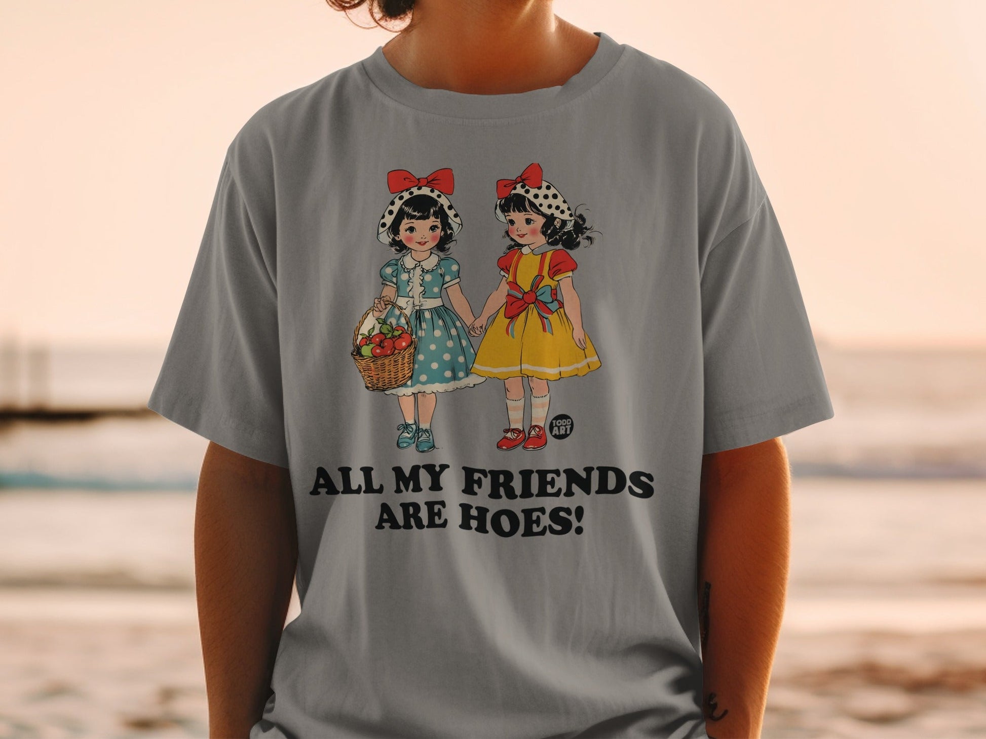 Grey t-shirt with vintage cartoon girls holding hands, one with a basket of apples.