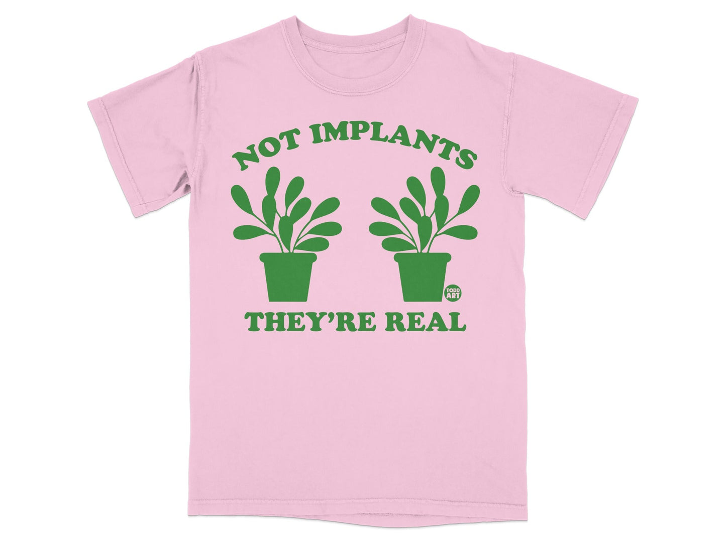 Pink t-shirt with green text and two potted plants: "NOT IMPLANTS THEY'RE REAL".