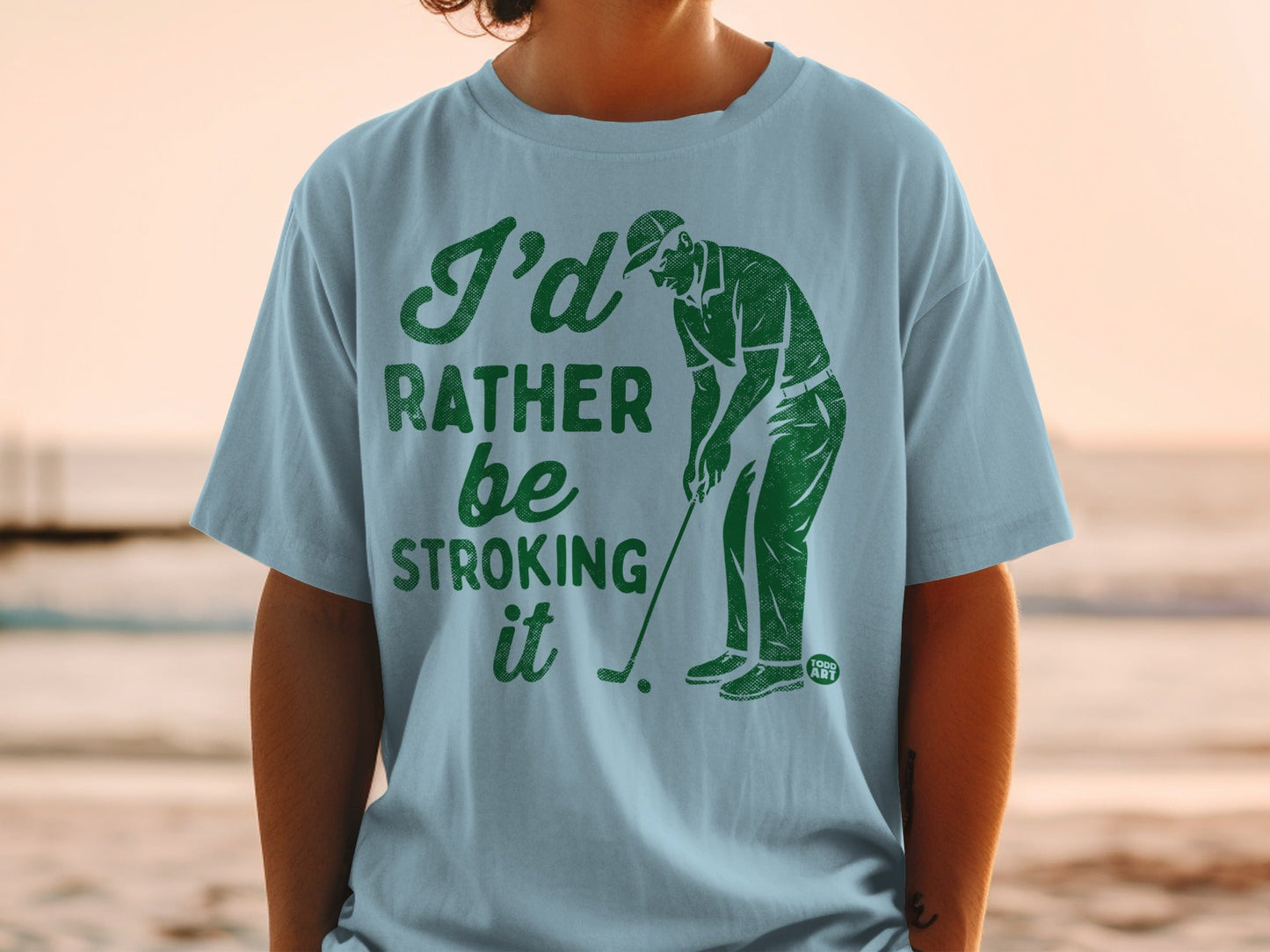 Light blue t-shirt with green text "I'd rather be stroking it" and a golf illustration.