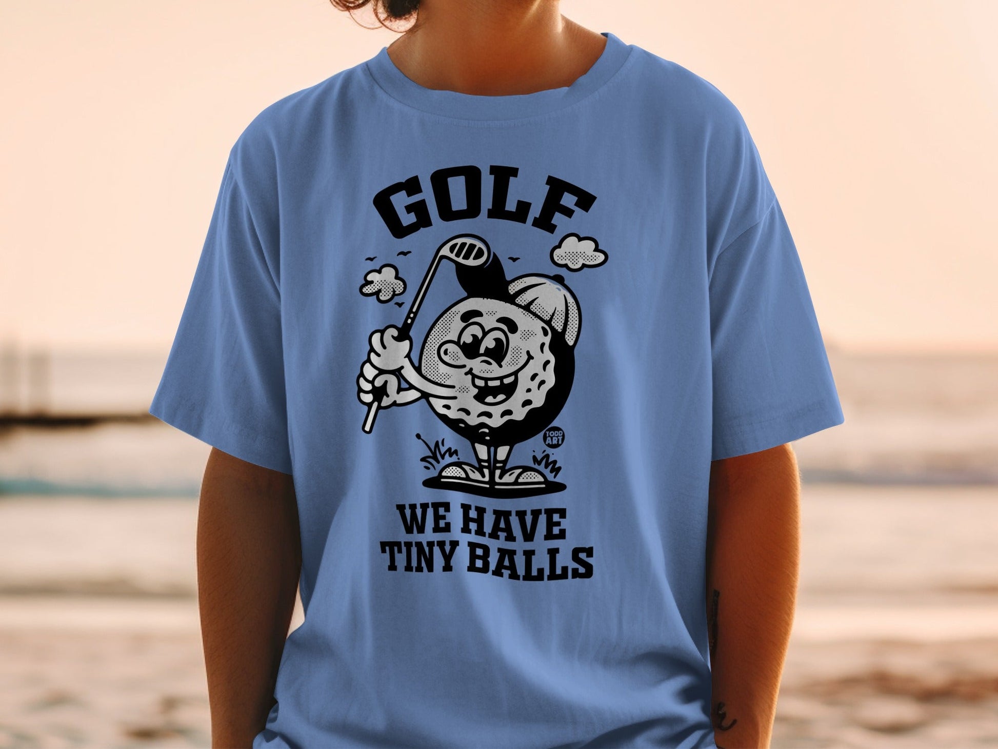 Light blue t-shirt with cartoon golf ball wearing a hat and holding a club.
