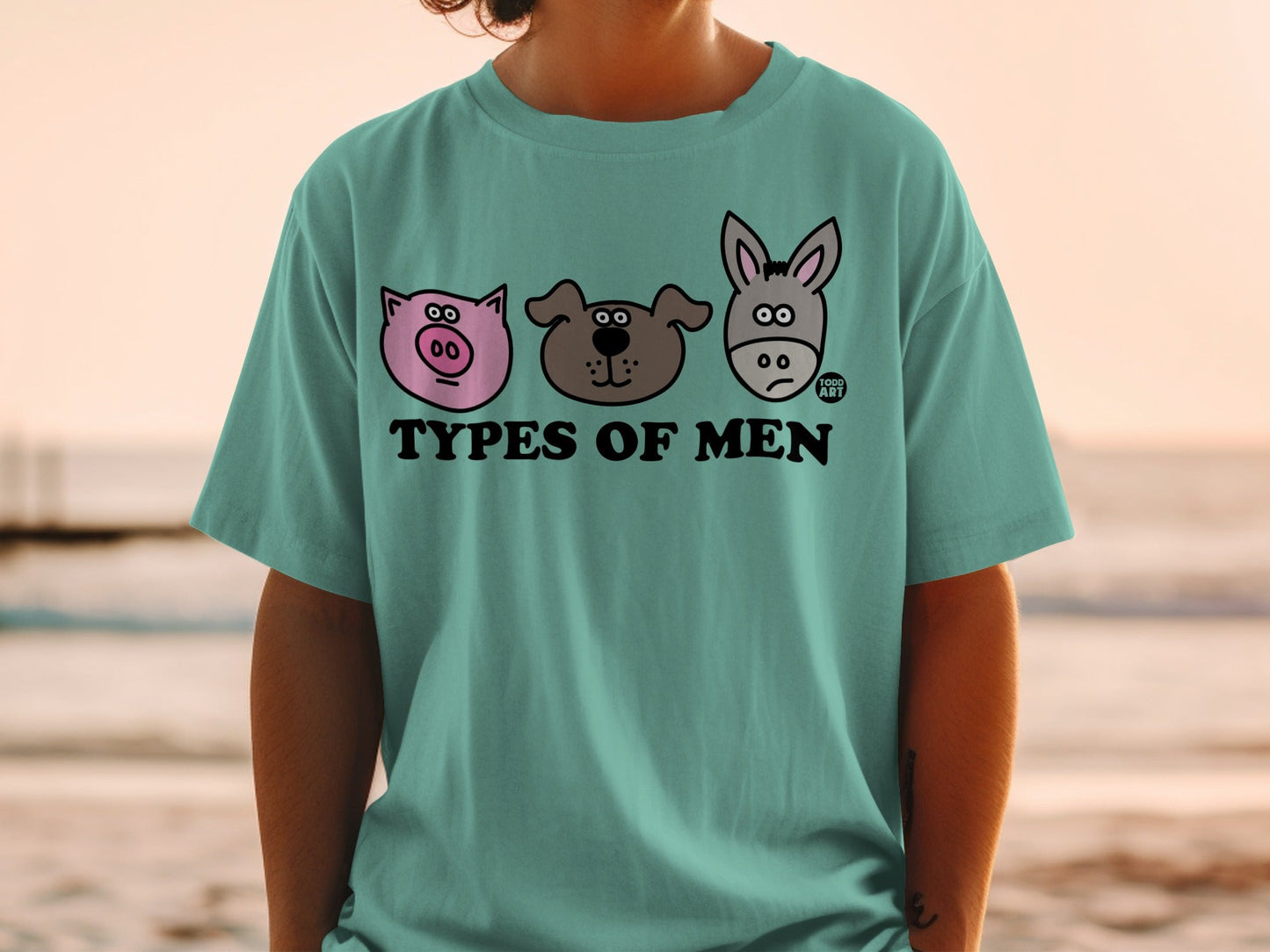 Teal t-shirt with cartoon pig, dog, and donkey heads and "TYPES OF MEN" text.