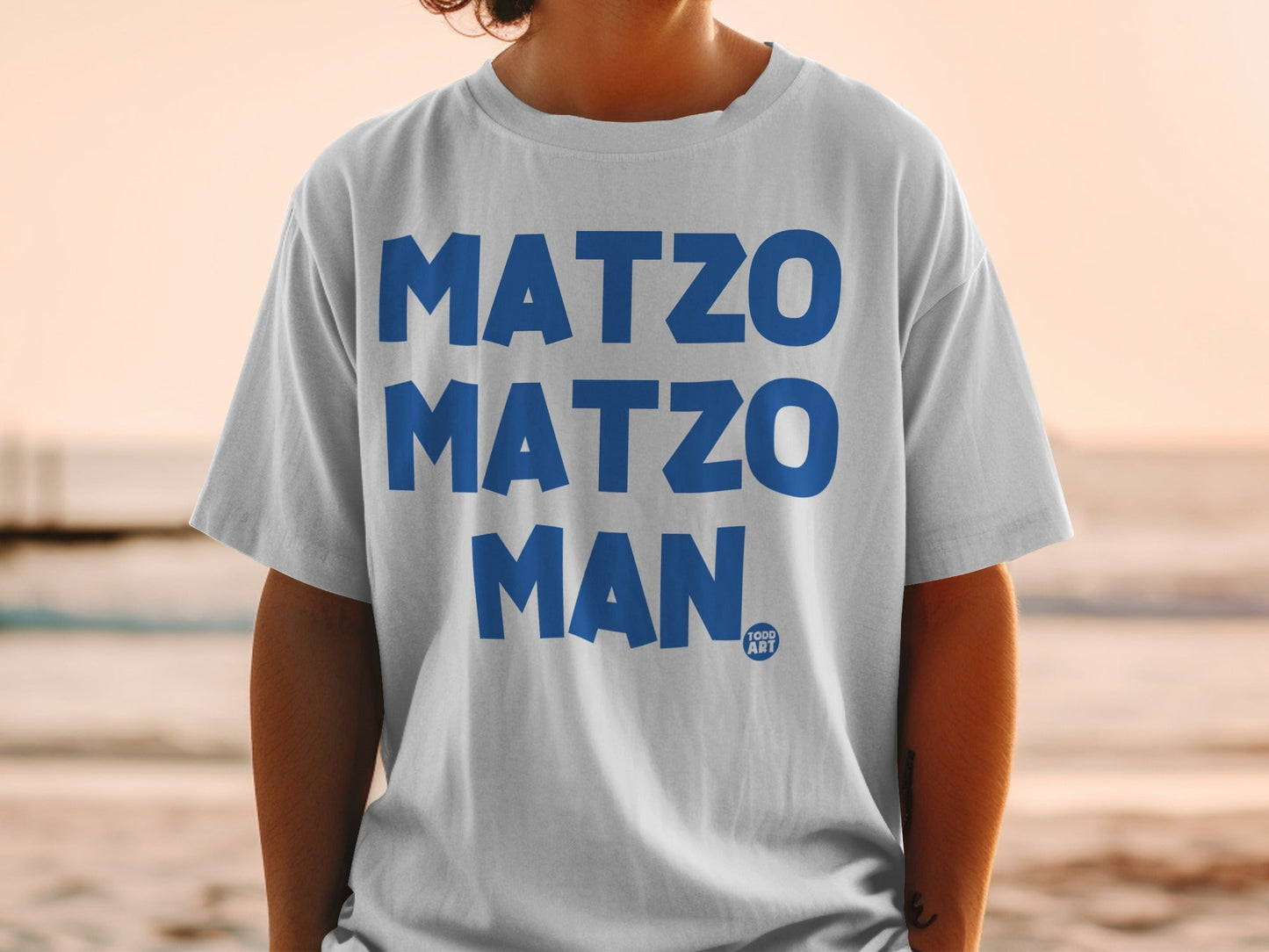 White t-shirt with blue "MATZO MATZO MAN" text and a small logo.