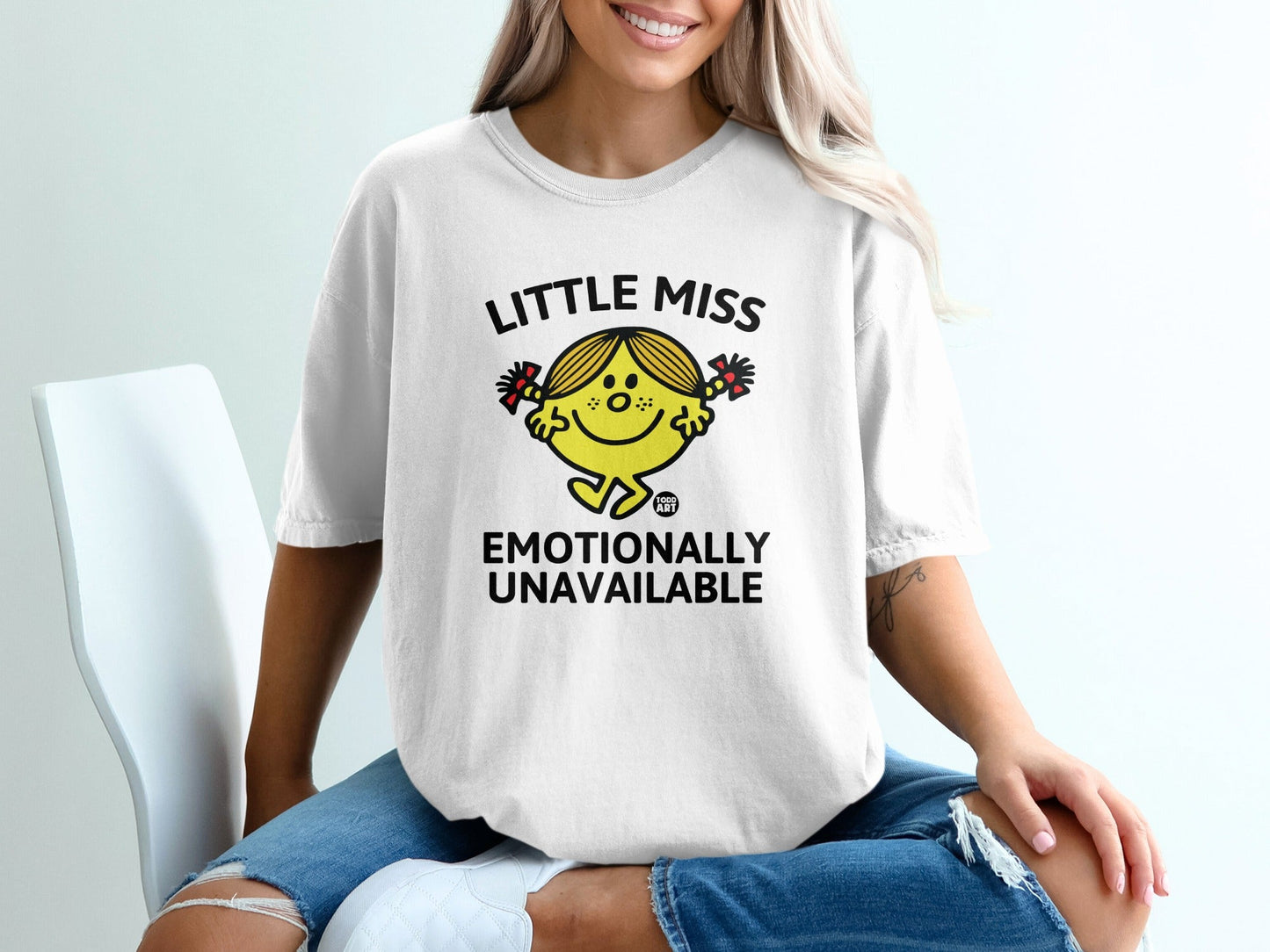 White t-shirt with "Little Miss Emotionally Unavailable" text and cartoon graphic.