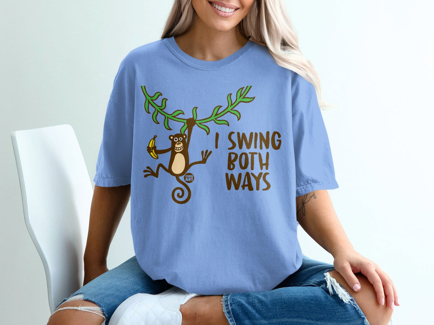 Blue t-shirt with cartoon monkey swinging from vine holding banana and text.