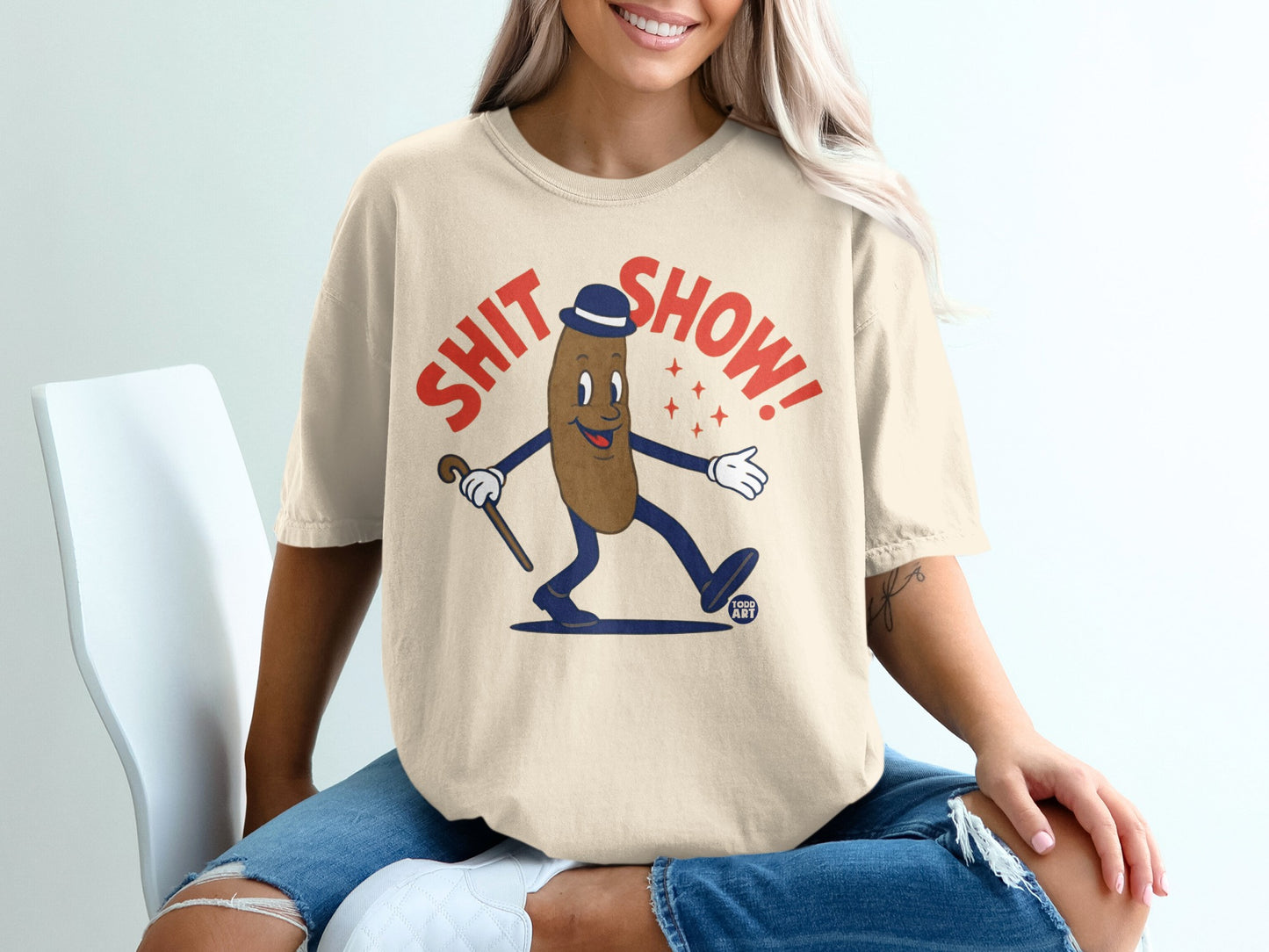 Cream t-shirt with cartoon poop character wearing a hat and holding a cane.