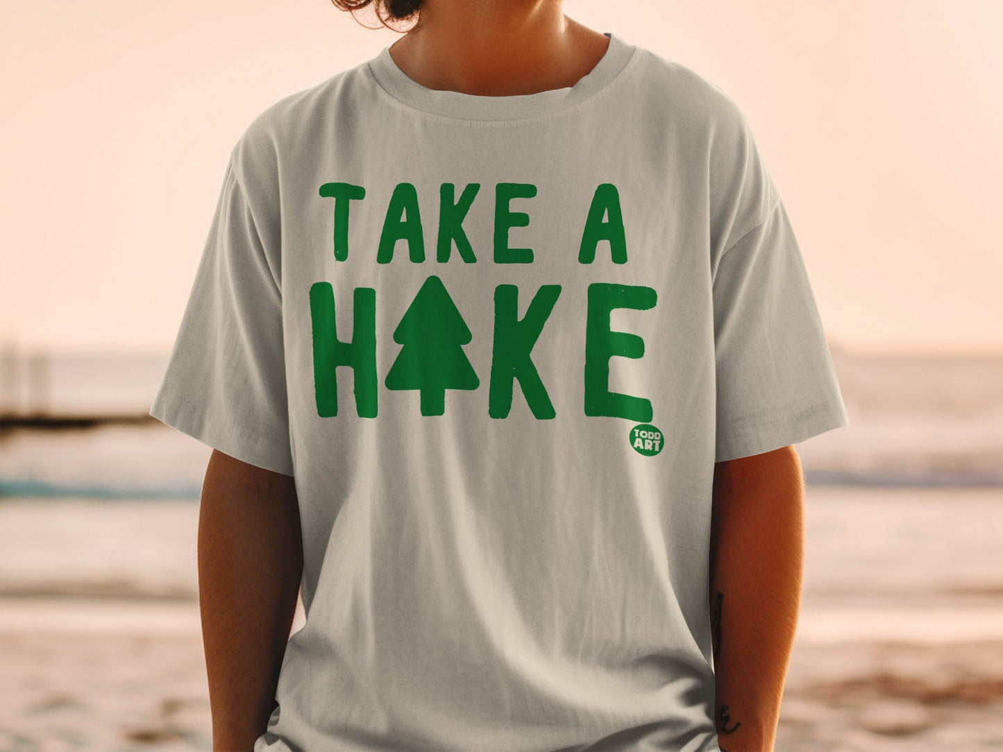Gray t-shirt with green "TAKE A HIKE" text and a small tree.