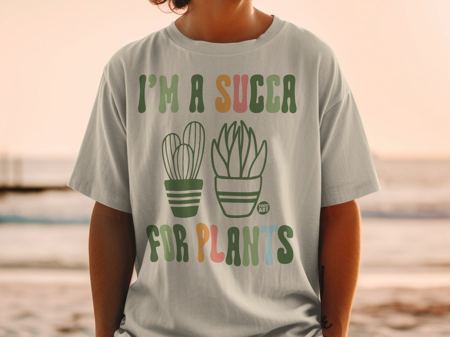 "I'm a succa for plants" text with cartoon cacti on a light green t-shirt.