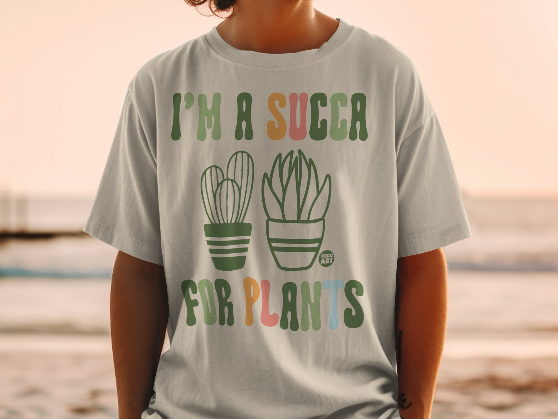 "I'm a succa for plants" text with cartoon cacti on a light green t-shirt.