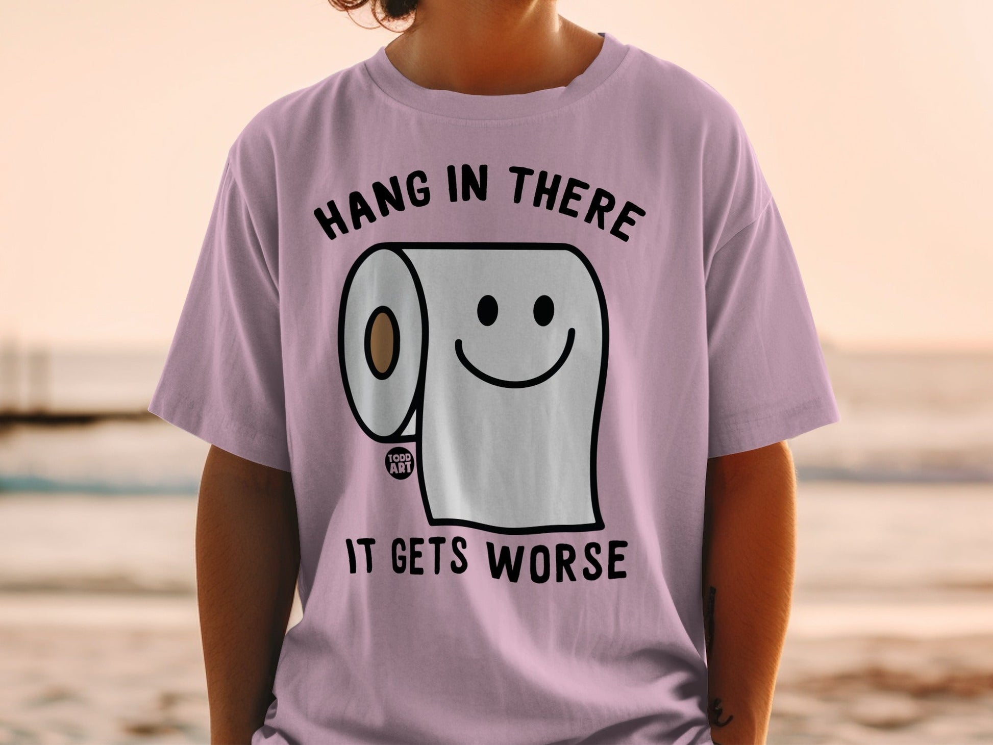 Light purple t-shirt with toilet paper character saying "Hang in there, it gets worse."