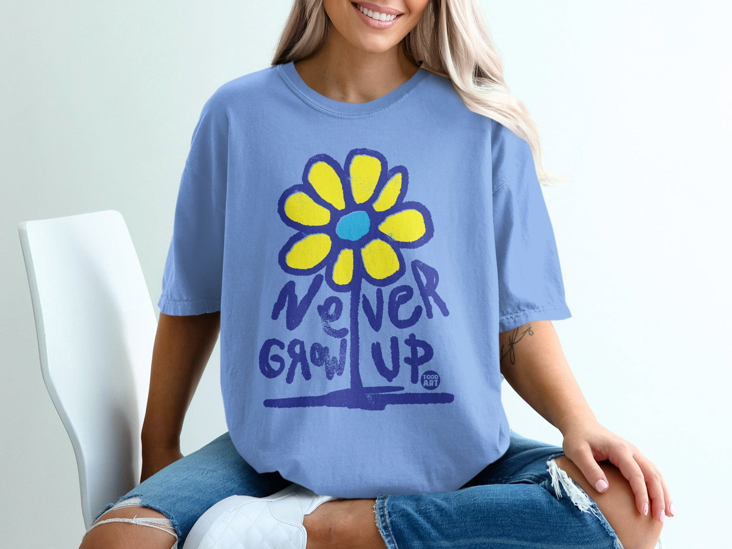 Blue t-shirt with yellow flower graphic and "Never Grow Up" text.