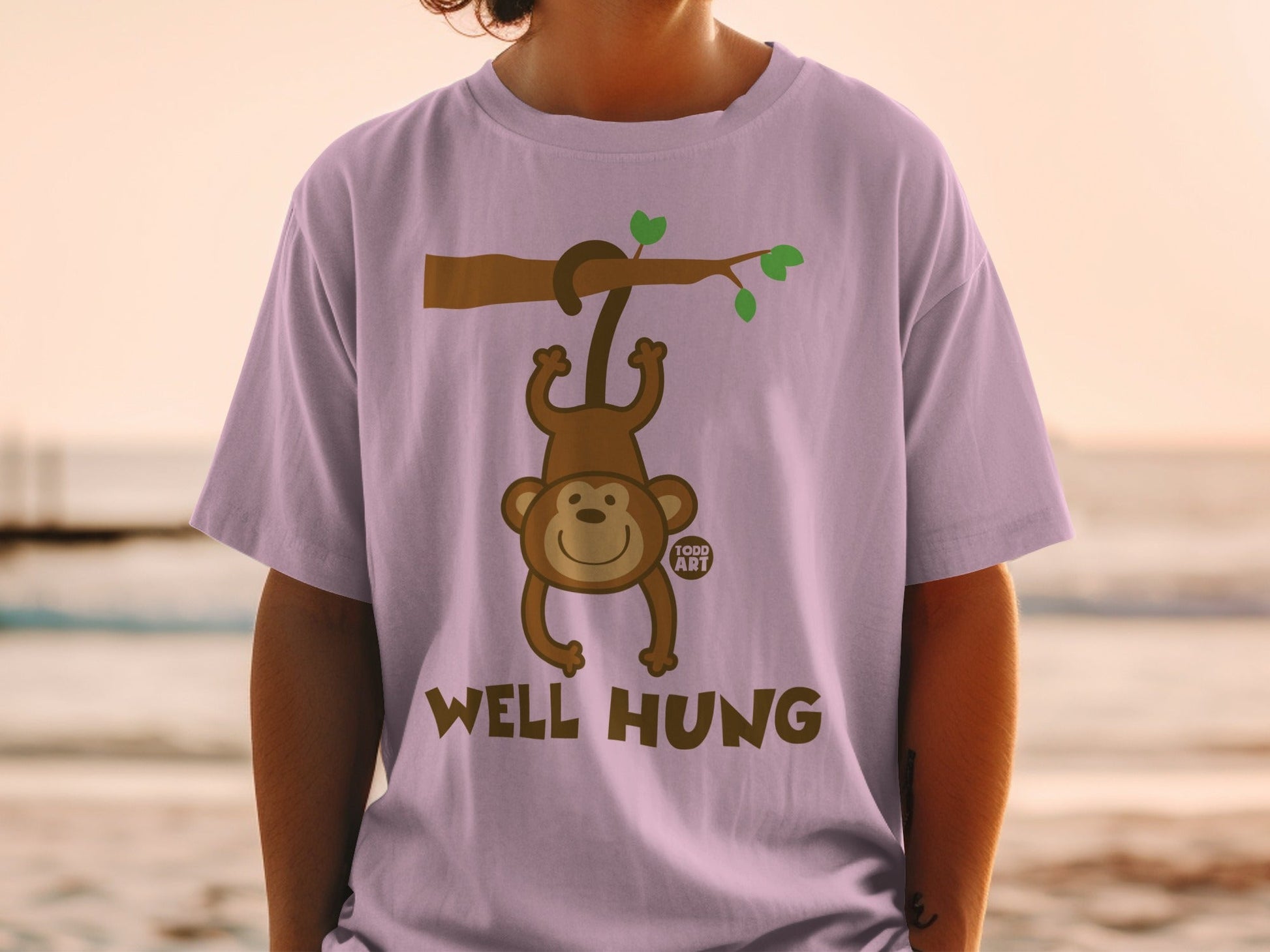 Light purple t-shirt with cartoon monkey hanging from a branch, text "WELL HUNG".
