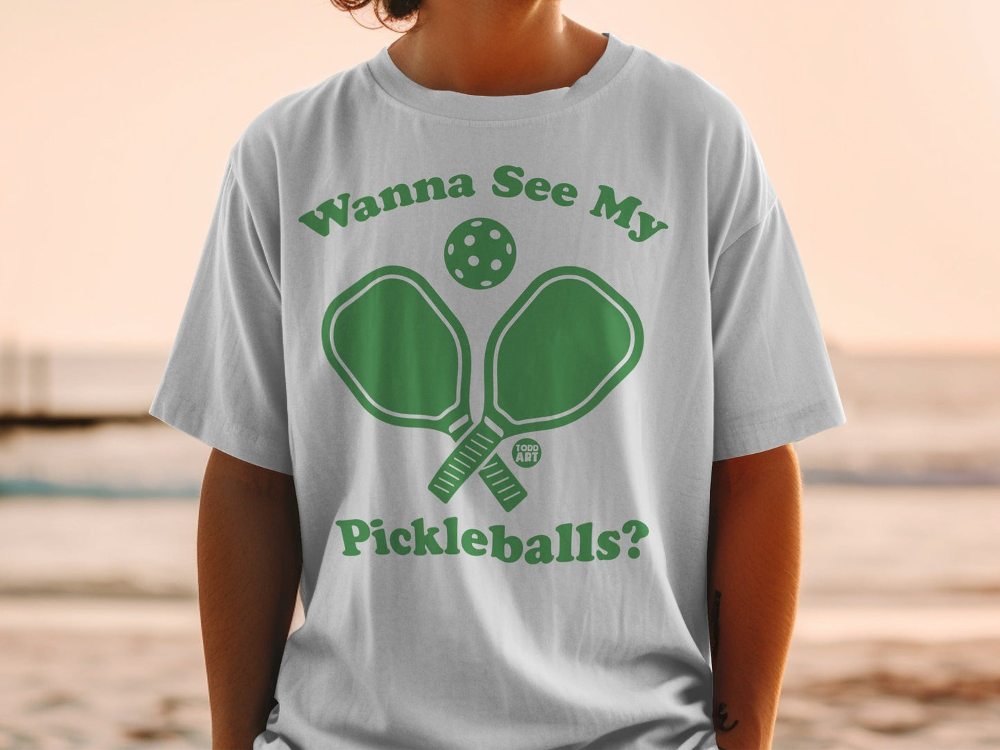White t-shirt with green pickleball graphic and text "Wanna See My Pickleballs?".