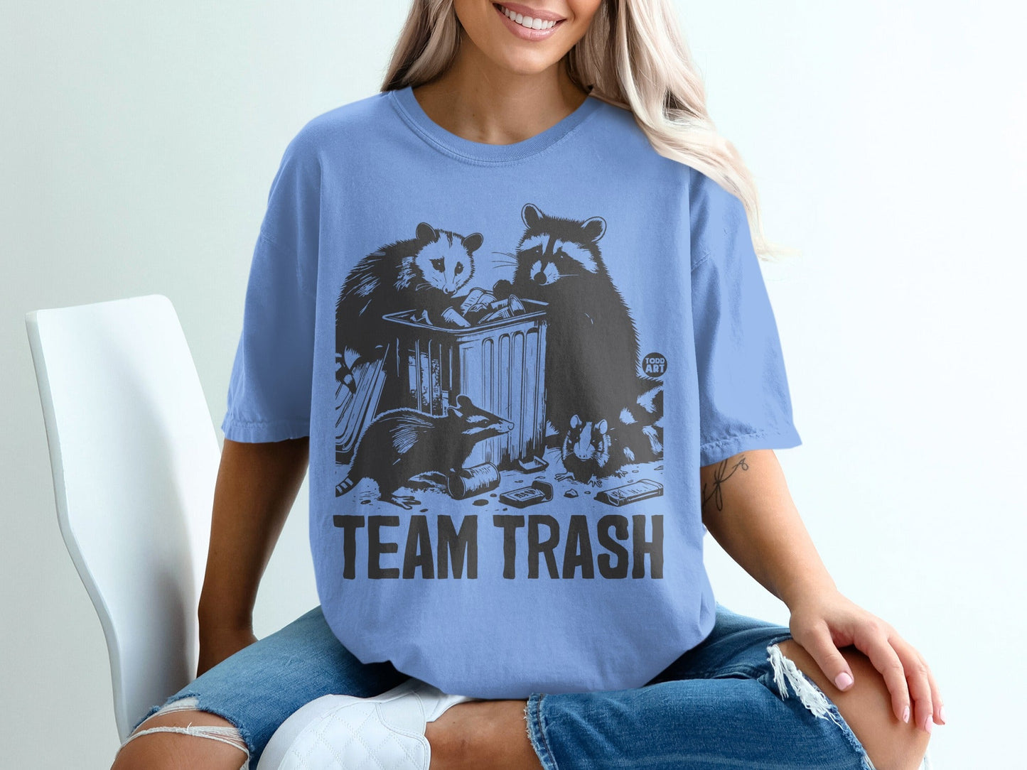 Graphic t-shirt with raccoons and an opossum near a trash can, reads "TEAM TRASH".