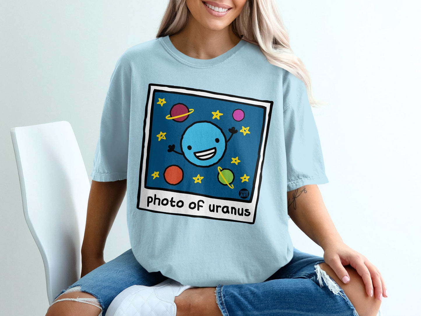Blue cartoon Uranus with stars and planets on light blue t-shirt.