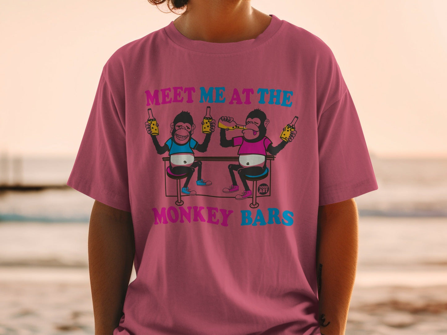T-shirt with cartoon monkeys holding beer bottles and text "MEET ME AT THE MONKEY BARS".