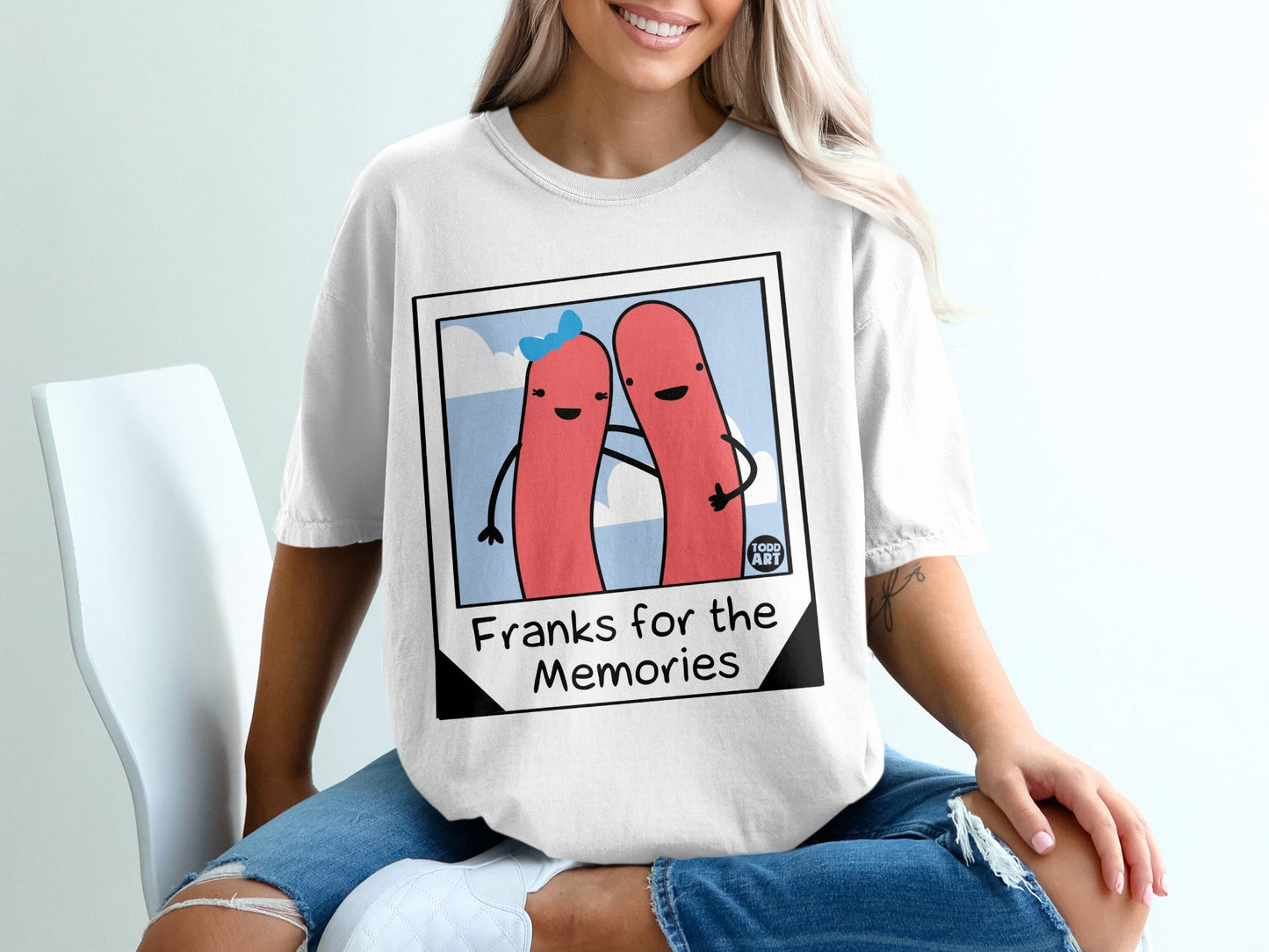 Two hot dogs with arms around each other, smiling, on a t-shirt.