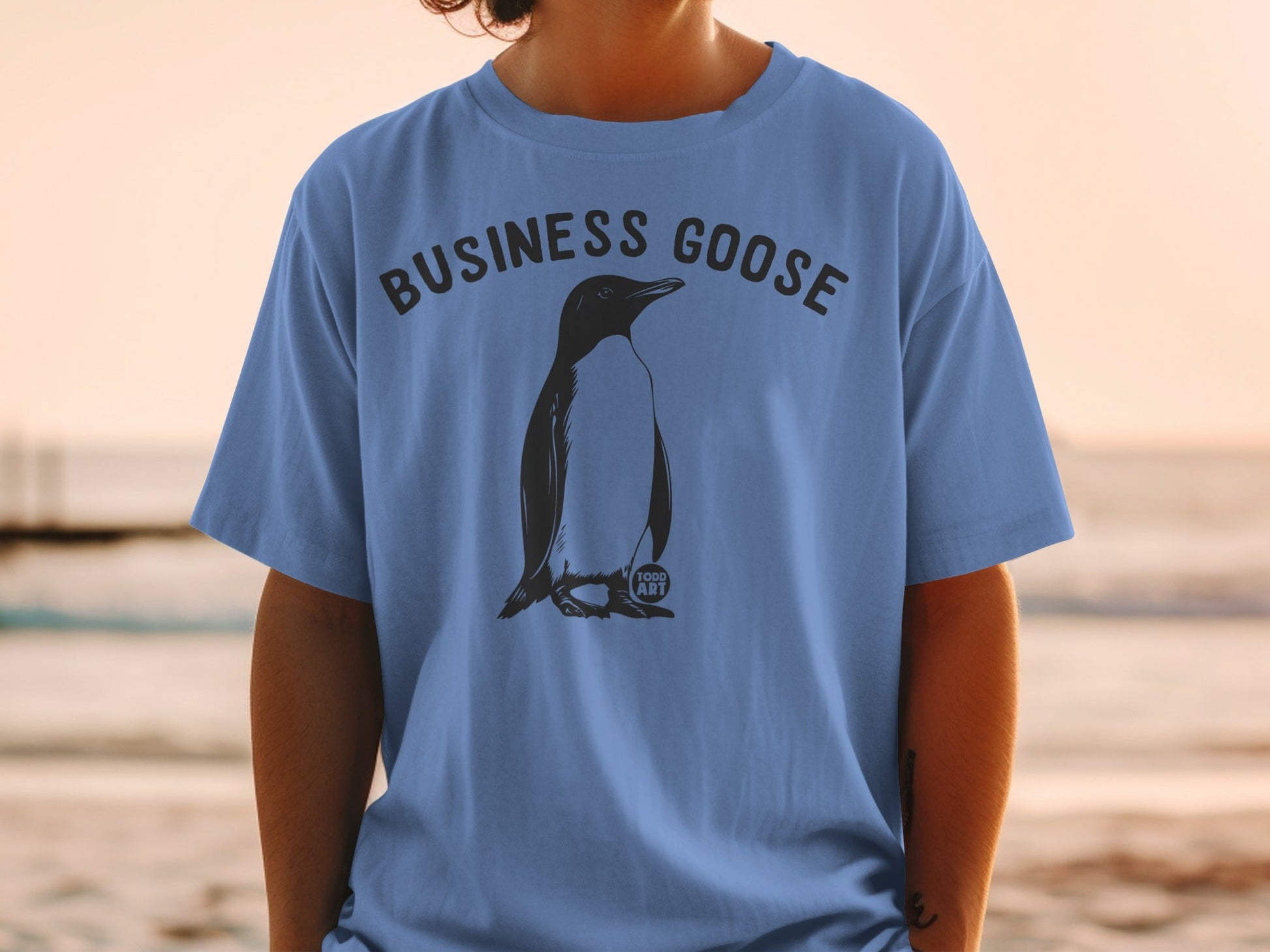 T-shirt with "BUSINESS GOOSE" text and penguin graphic on blue fabric.