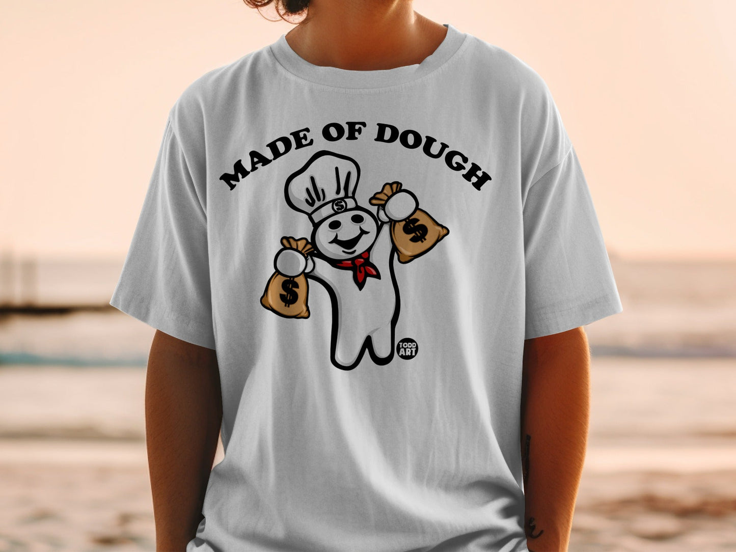 Pillsbury Doughboy wearing chef hat and holding money bags on a white t-shirt.