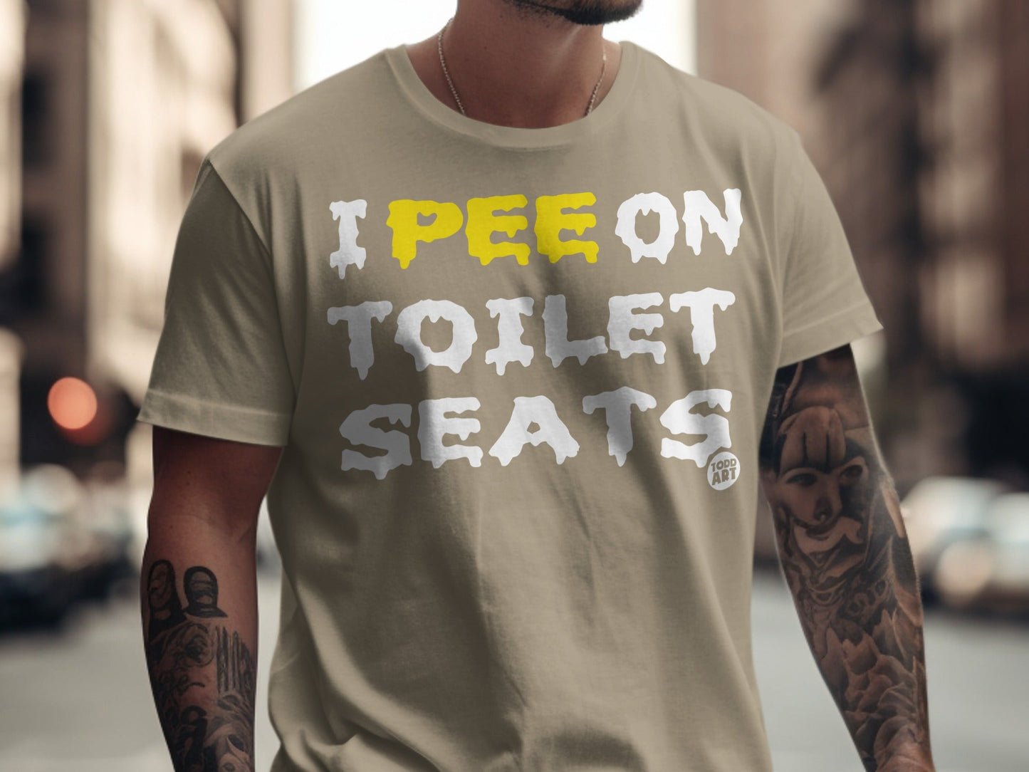 Tan t-shirt with "I PEE ON TOILET SEATS" graphic in yellow and white.