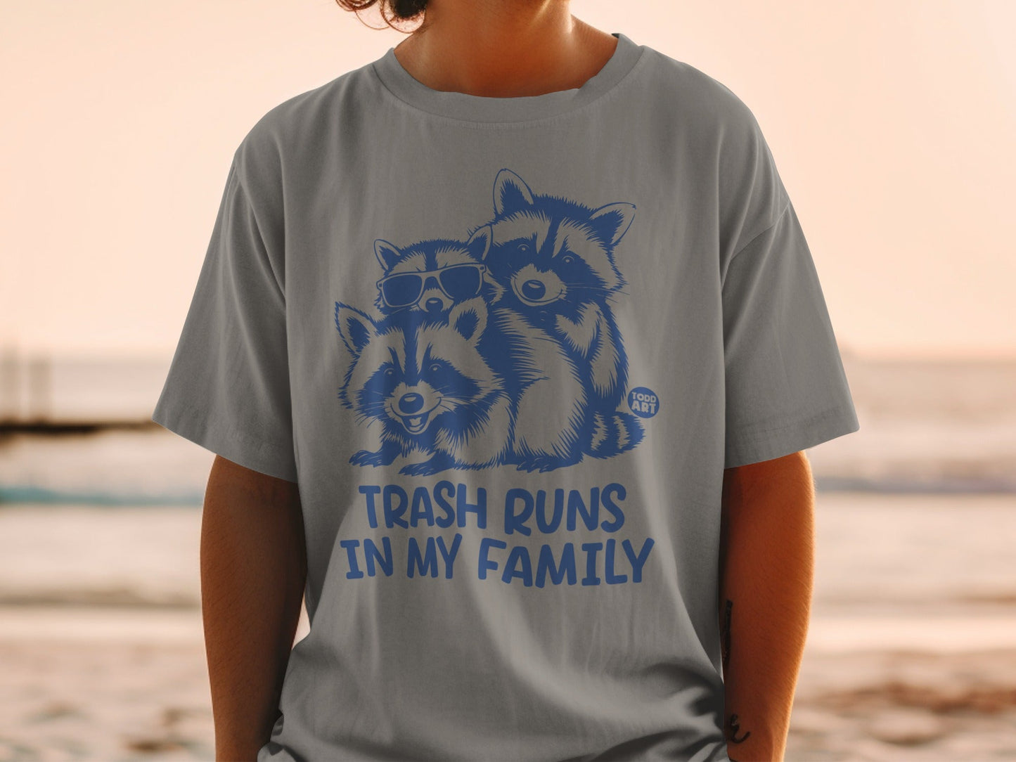 T-shirt with three raccoons wearing sunglasses, text "trash runs in my family".