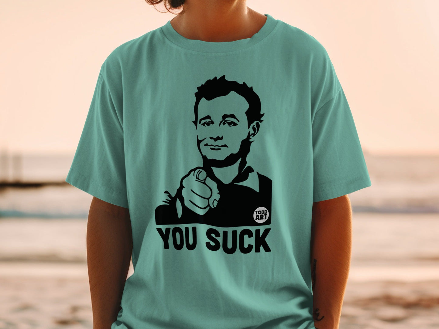 Bill Murray pointing, wearing a teal t-shirt with "YOU SUCK" text.