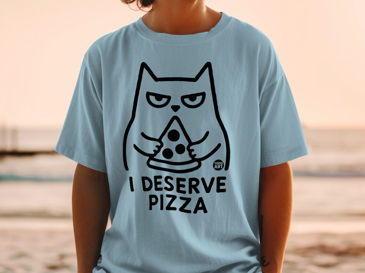 Light blue t-shirt with black outline of a grumpy cat eating pizza, text reads "I DESERVE PIZZA".