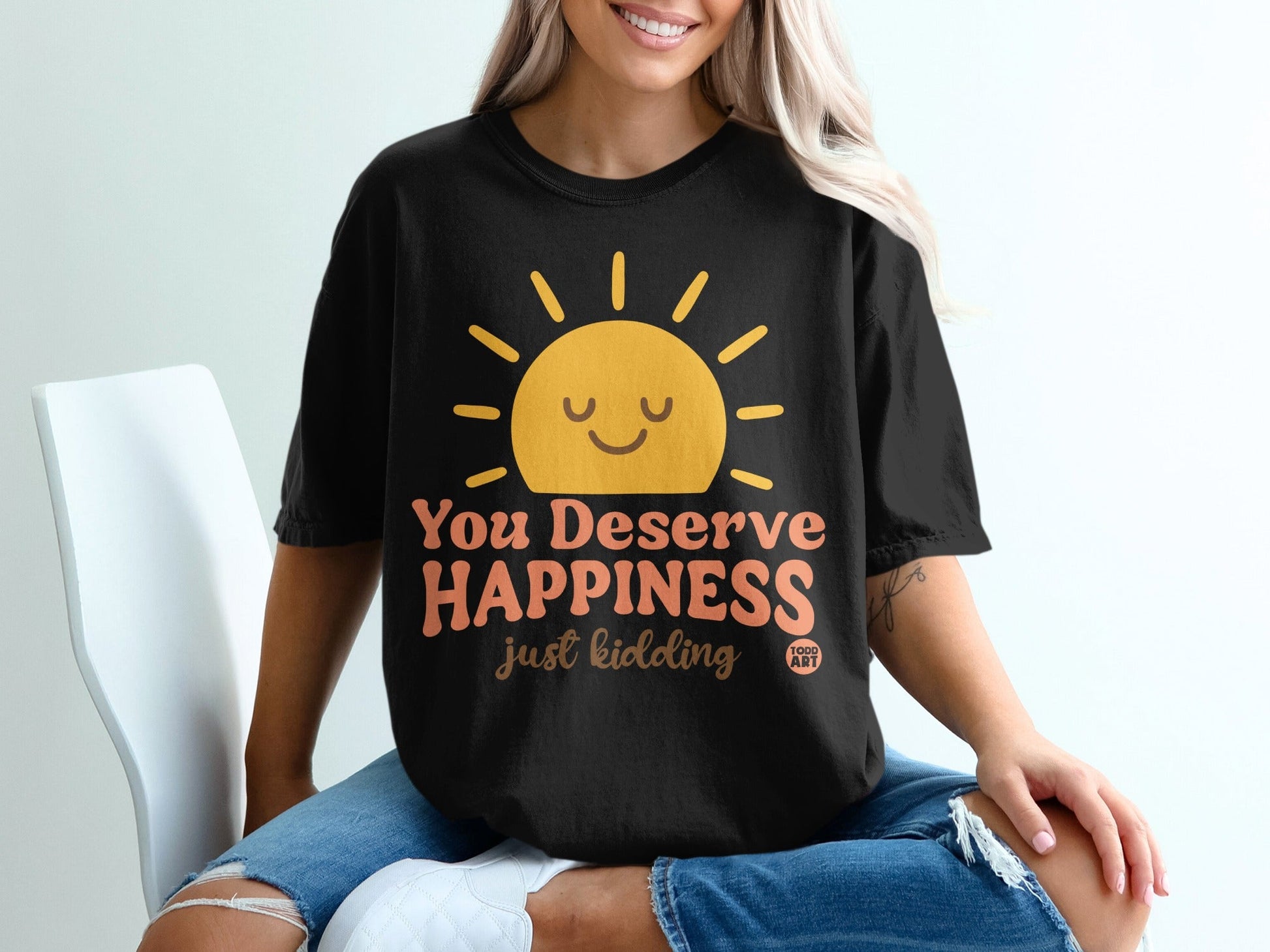 Black t-shirt with a smiling sun graphic and text that reads "You Deserve Happiness just kidding".