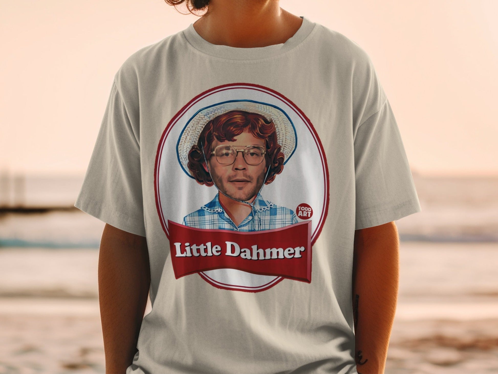 T-shirt featuring circular portrait of a man with glasses and hat, text "Little Dahmer" below.