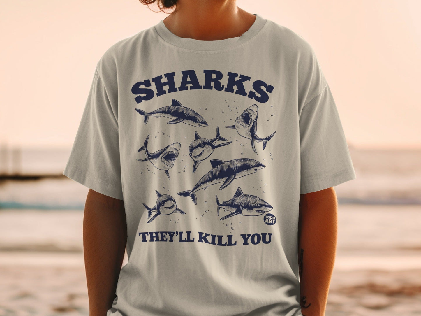 T-shirt with graphic illustration of sharks and text "SHARKS THEY'LL KILL YOU".