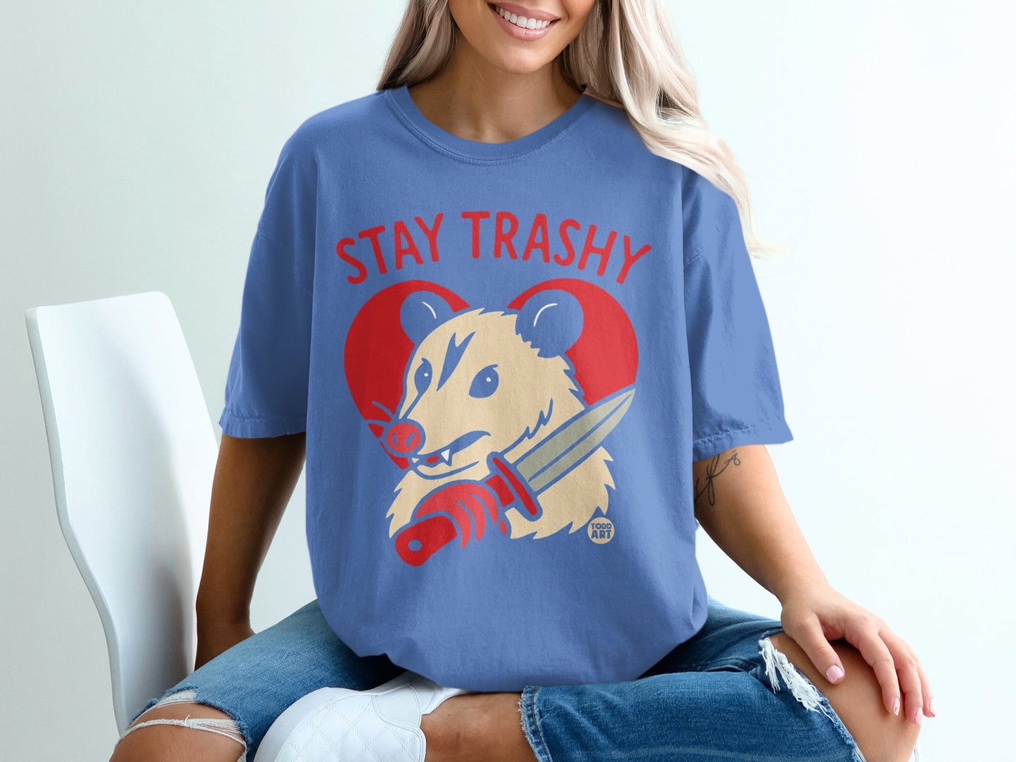 Blue t-shirt with red heart and possum holding a knife, text reads "Stay Trashy".