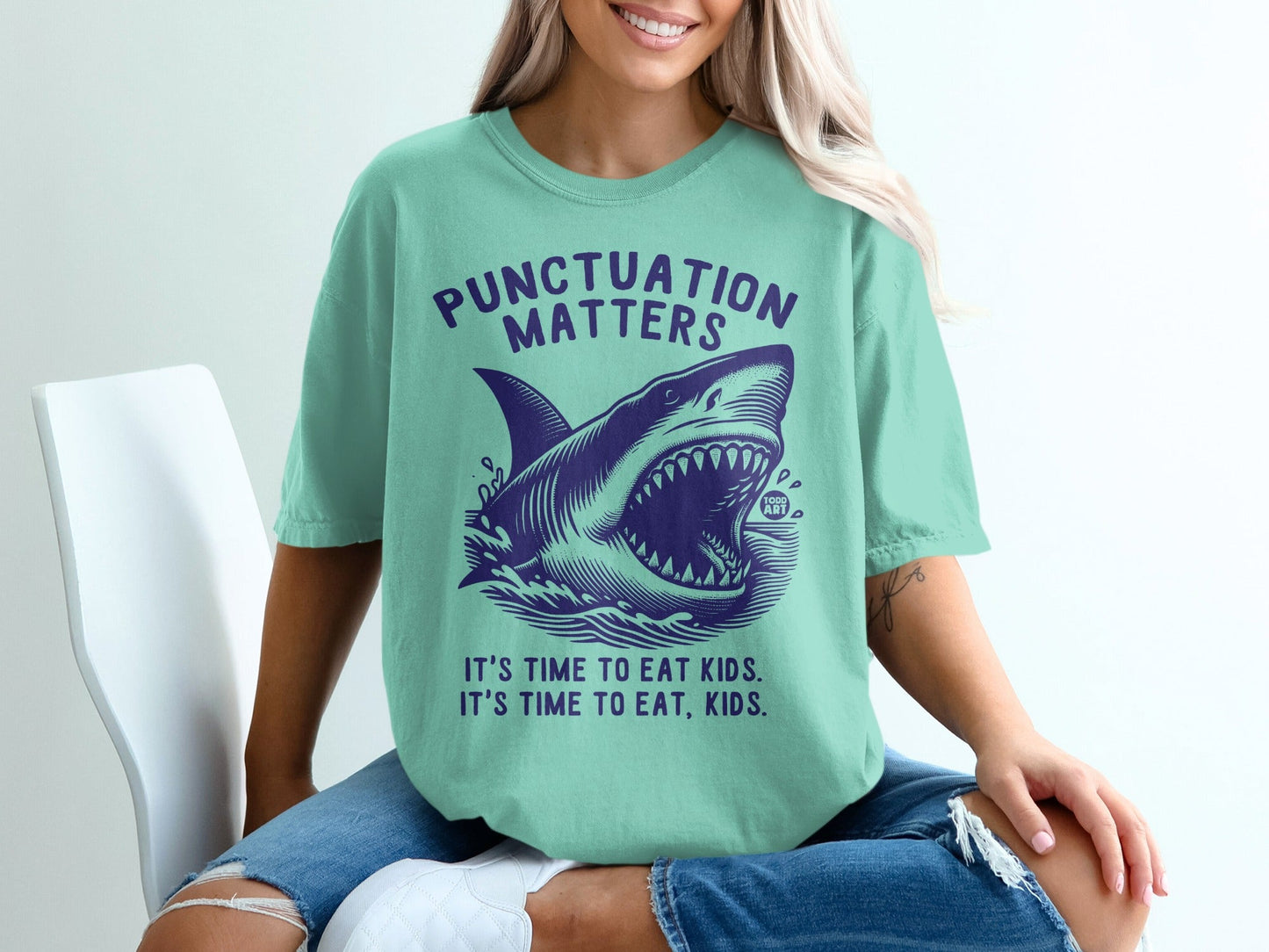 T-shirt with shark graphic and text "Punctuation Matters, It's Time to Eat Kids."