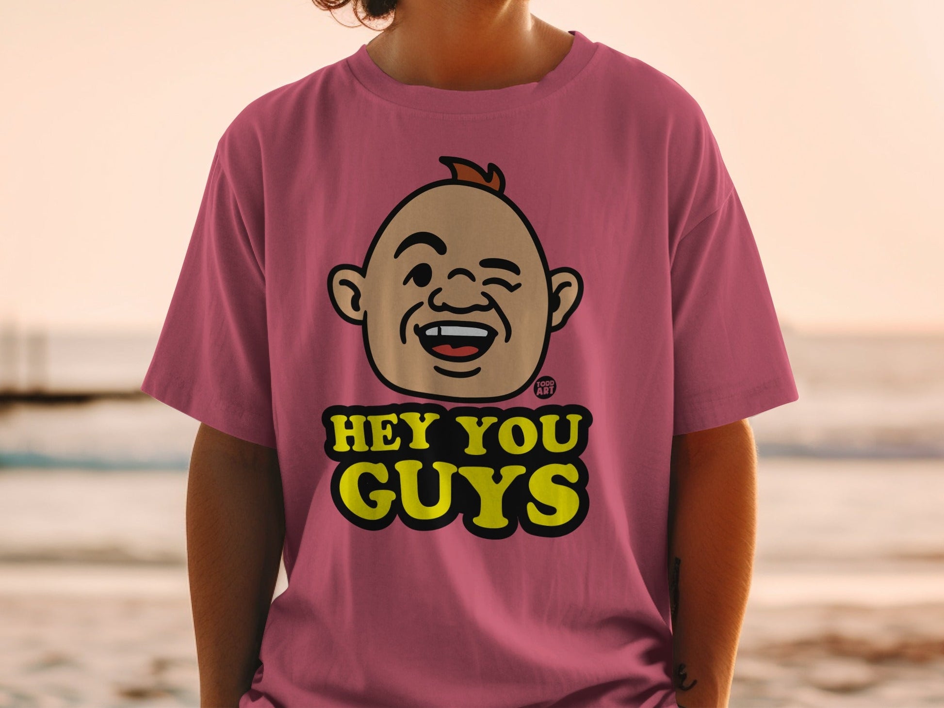 Pink t-shirt with a cartoon face and "HEY YOU GUYS" text.