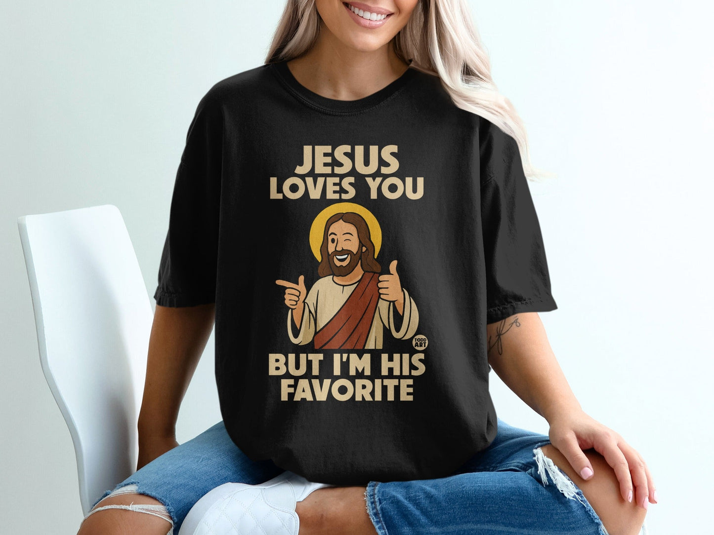 Black t-shirt with "Jesus Loves You But I'm His Favorite" text and cartoon Jesus.