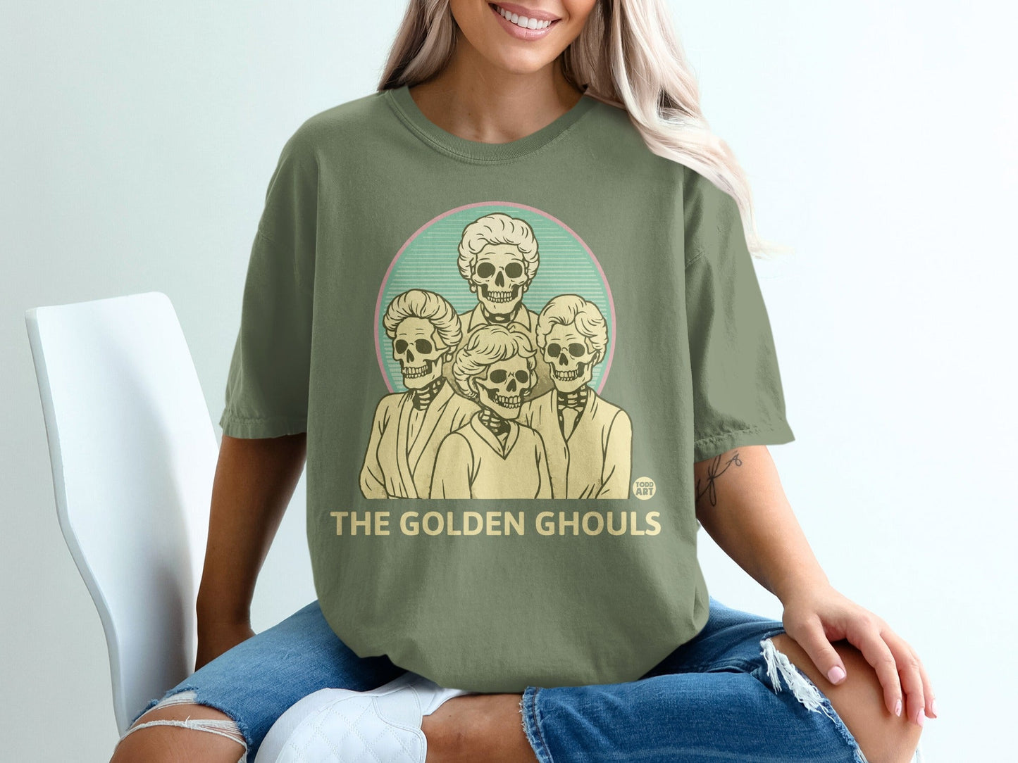 Olive green t-shirt with "The Golden Ghouls" and skeleton portraits.