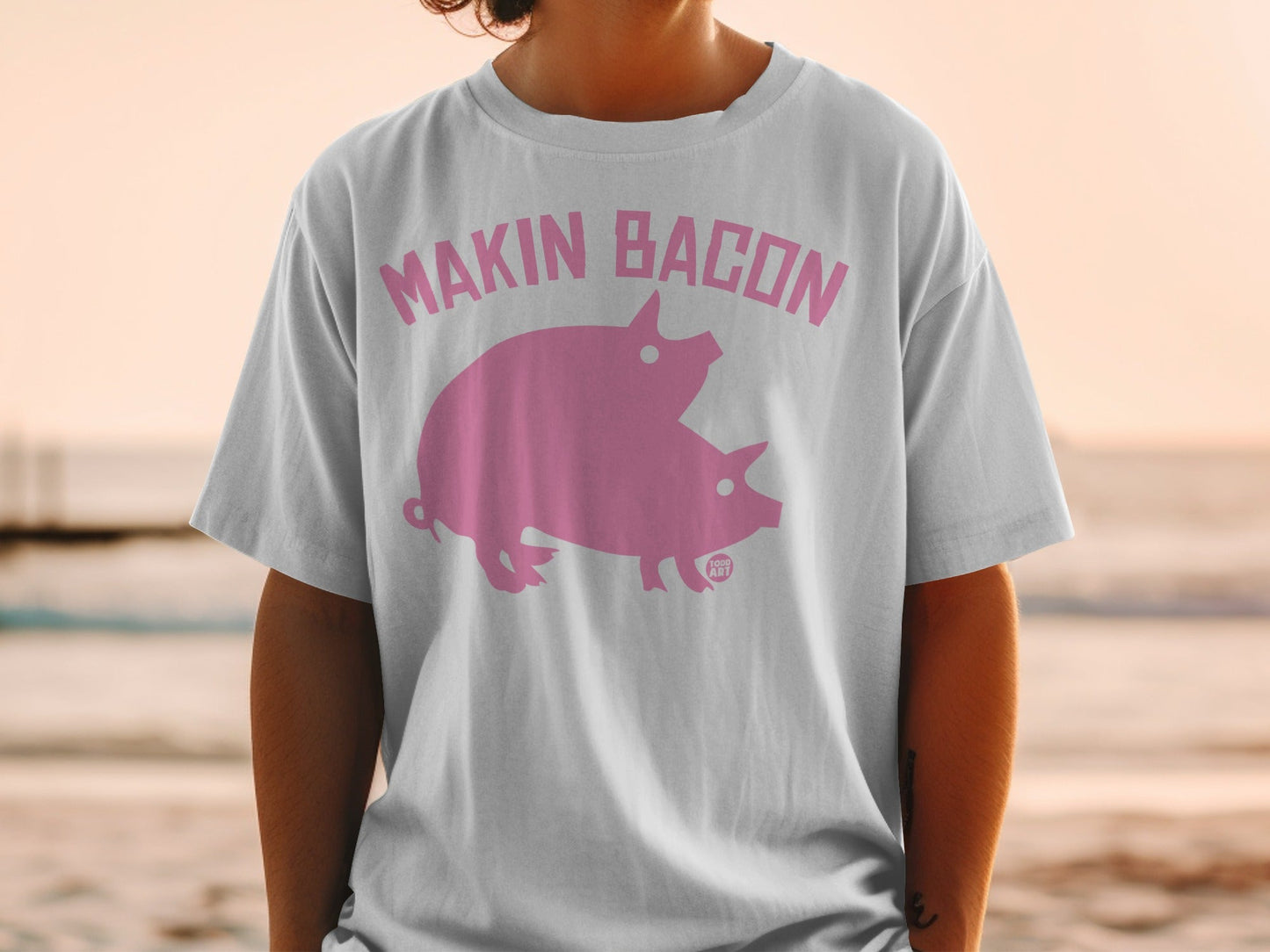 White t-shirt with pink "Makin' Bacon" text and two pigs.