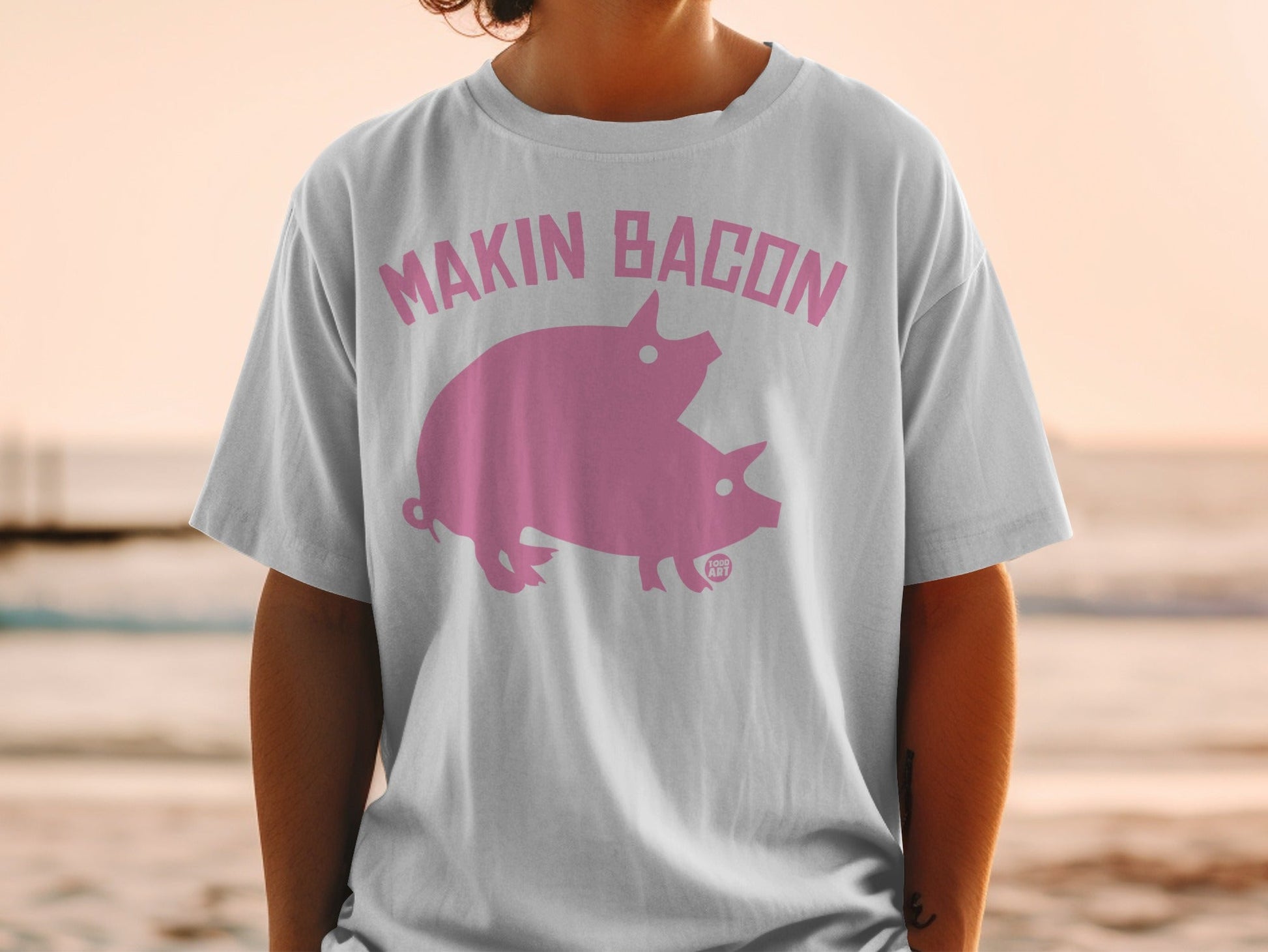 White t-shirt with pink "Makin' Bacon" text and two pigs.