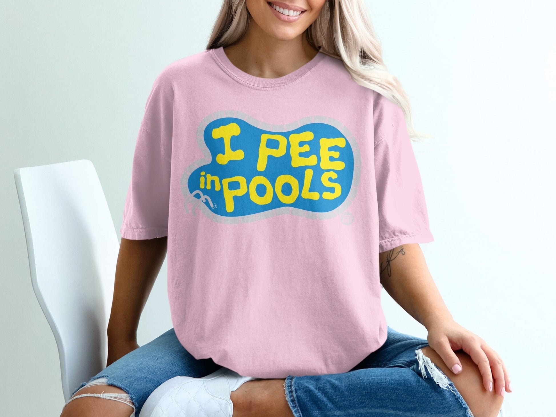 Pink t-shirt with yellow text "I PEE IN POOLS" in a blue bubble.