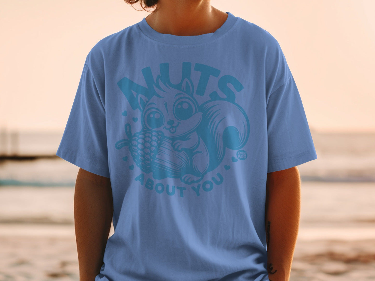 Light blue t-shirt with cartoon squirrel holding a pinecone and text "NUTS ABOUT YOU".
