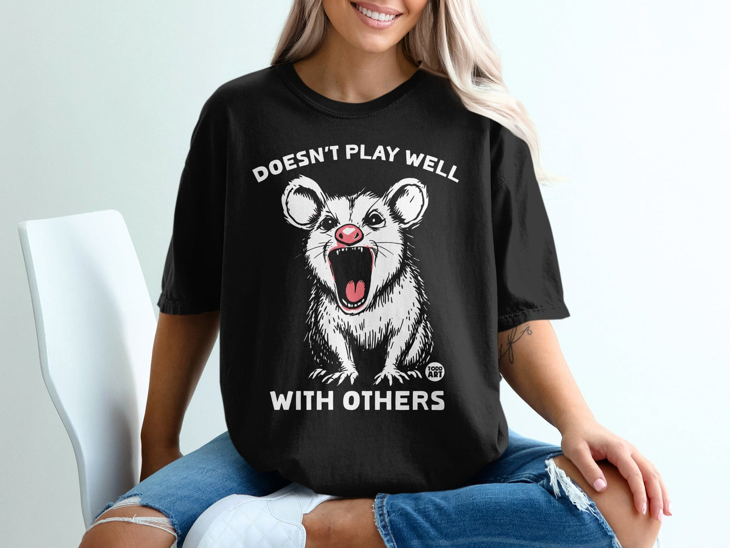 Black t-shirt with white possum and text "Doesn't Play Well With Others."