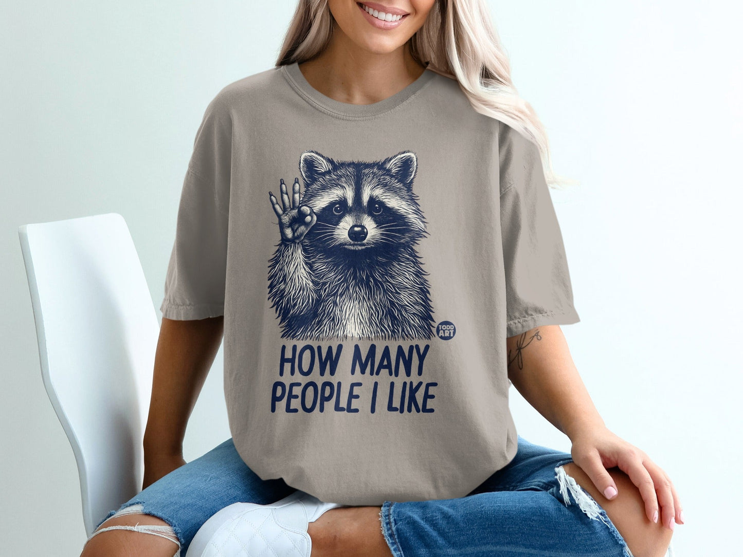 T-shirt with raccoon graphic and "How Many People I Like" text.