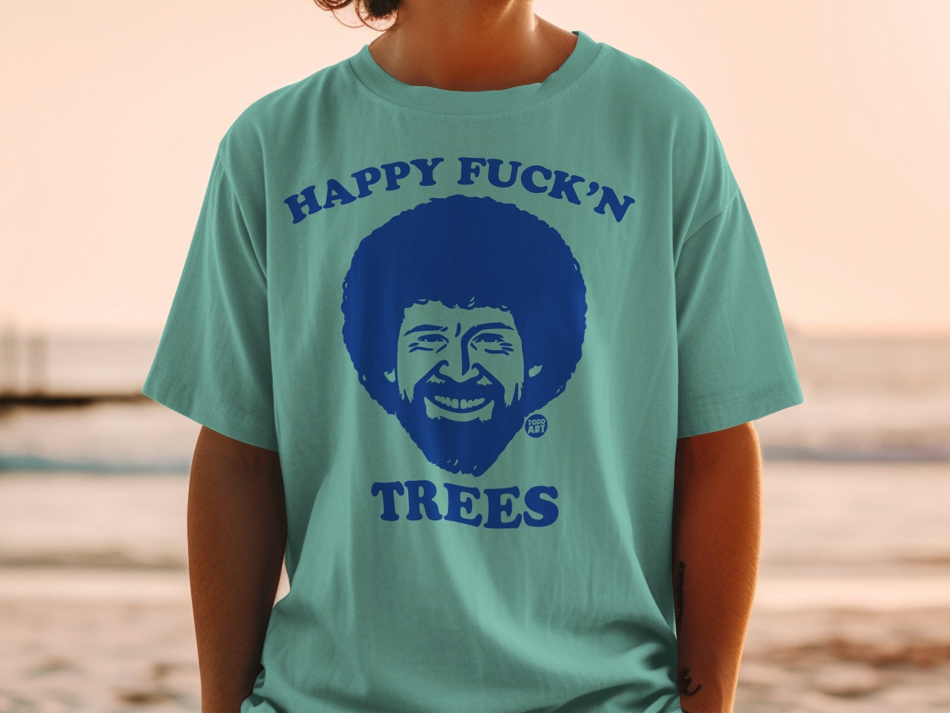 Teal t-shirt with Bob Ross graphic and "Happy Fuck'n Trees" text.