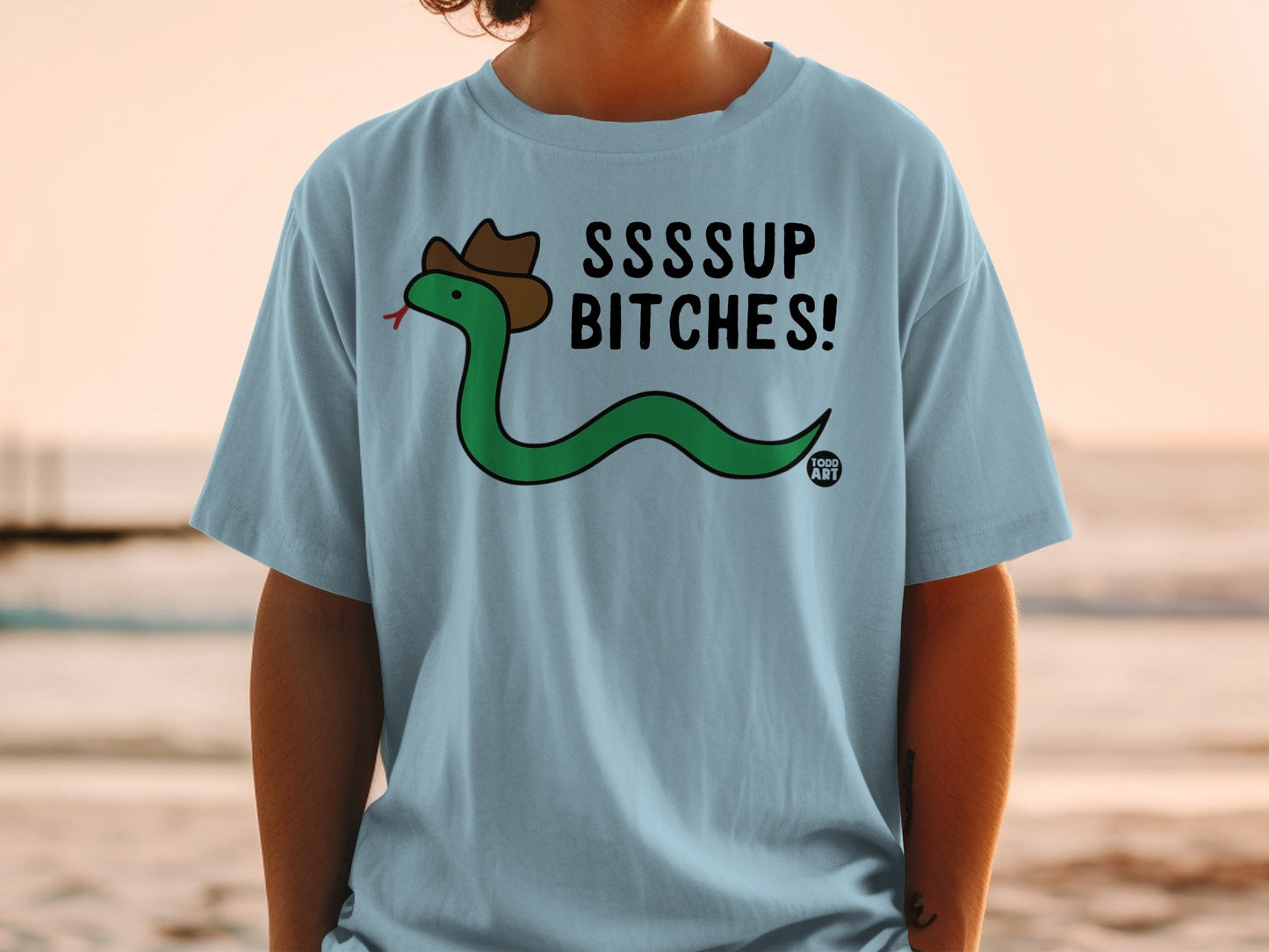 Blue t-shirt with cartoon snake in cowboy hat saying "SSSUP BITCHES!"