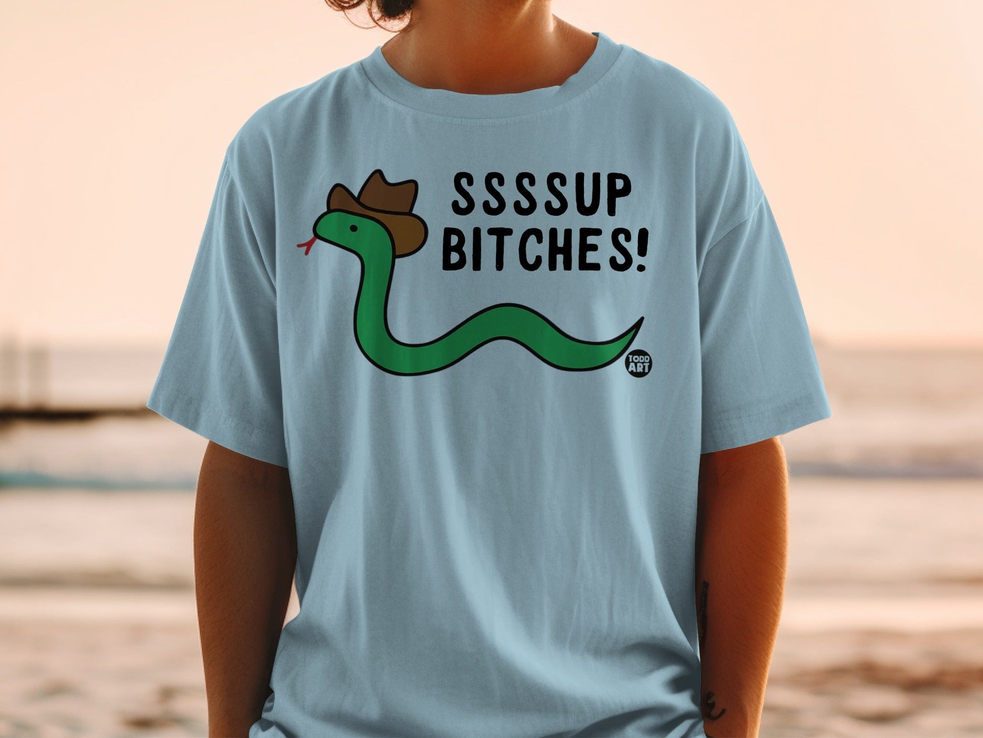 Blue t-shirt with cartoon snake in cowboy hat saying "SSSUP BITCHES!"