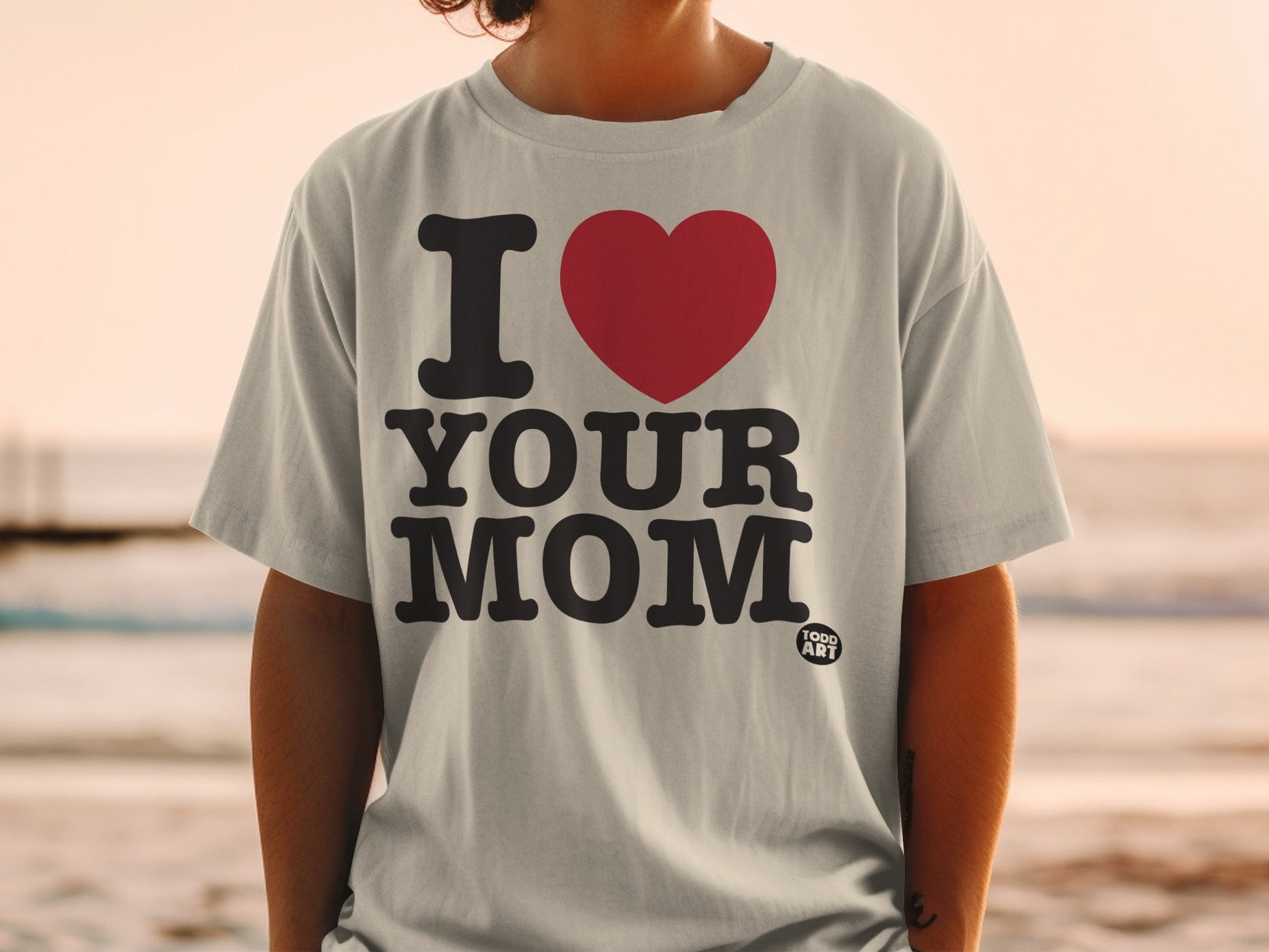 Grey t-shirt with "I ‚ù§Ô∏è YOUR MOM" graphic and small "GOOD ART" logo.