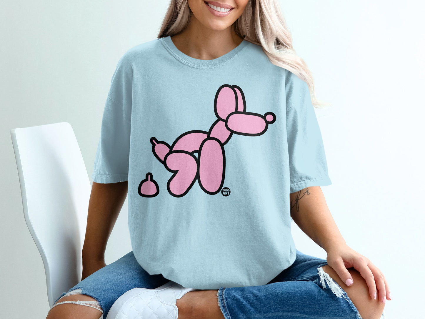 Light blue t-shirt with a pink balloon dog and pile of poop graphic.