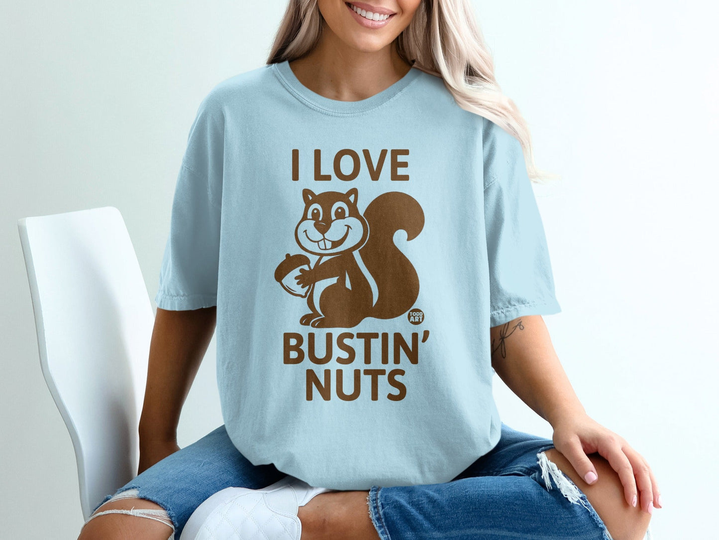 Light blue t-shirt with a cartoon squirrel holding a nut and text that reads "I LOVE BUSTIN' NUTS".