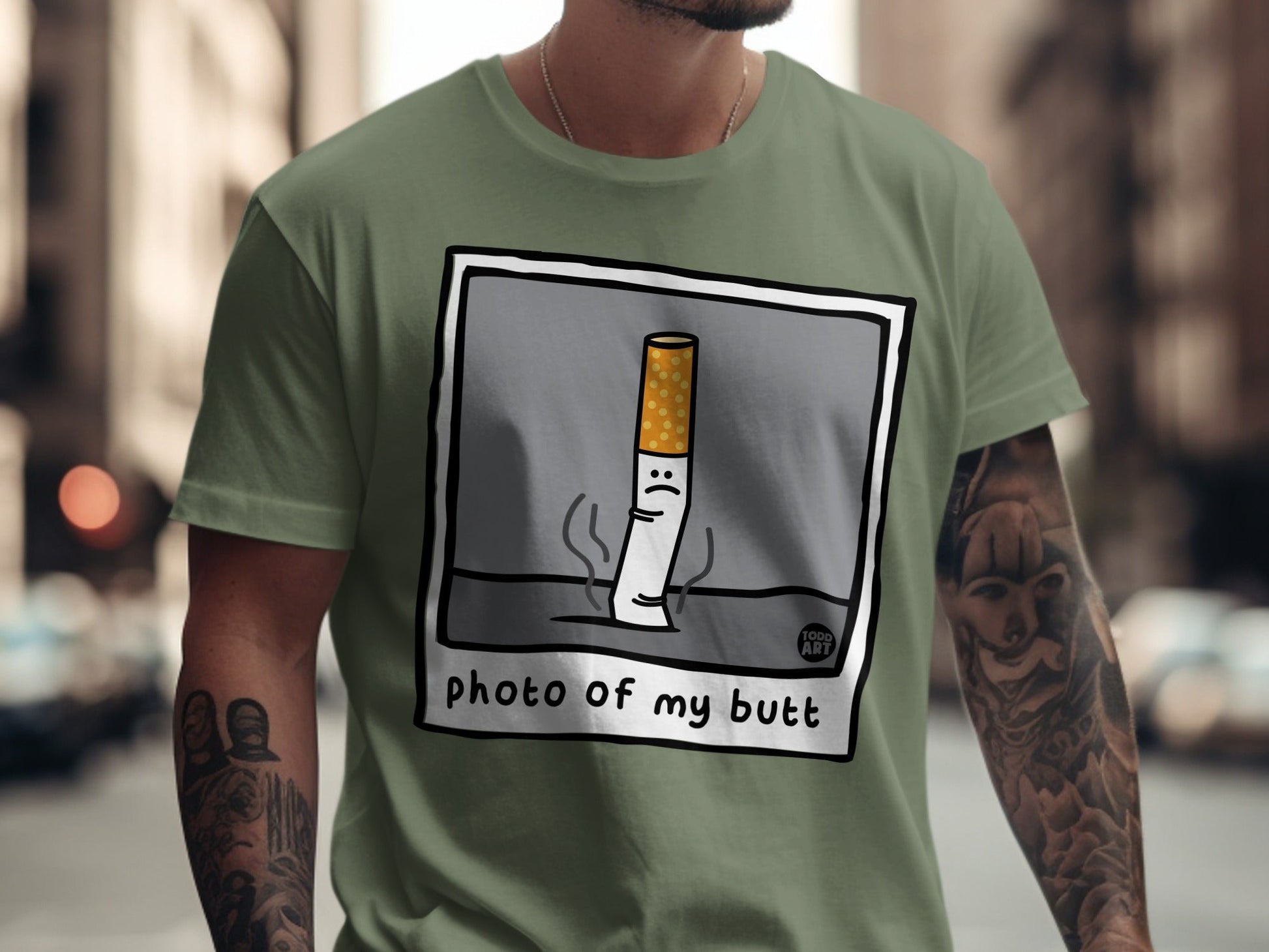 Cartoon cigarette with sad face on green t-shirt.