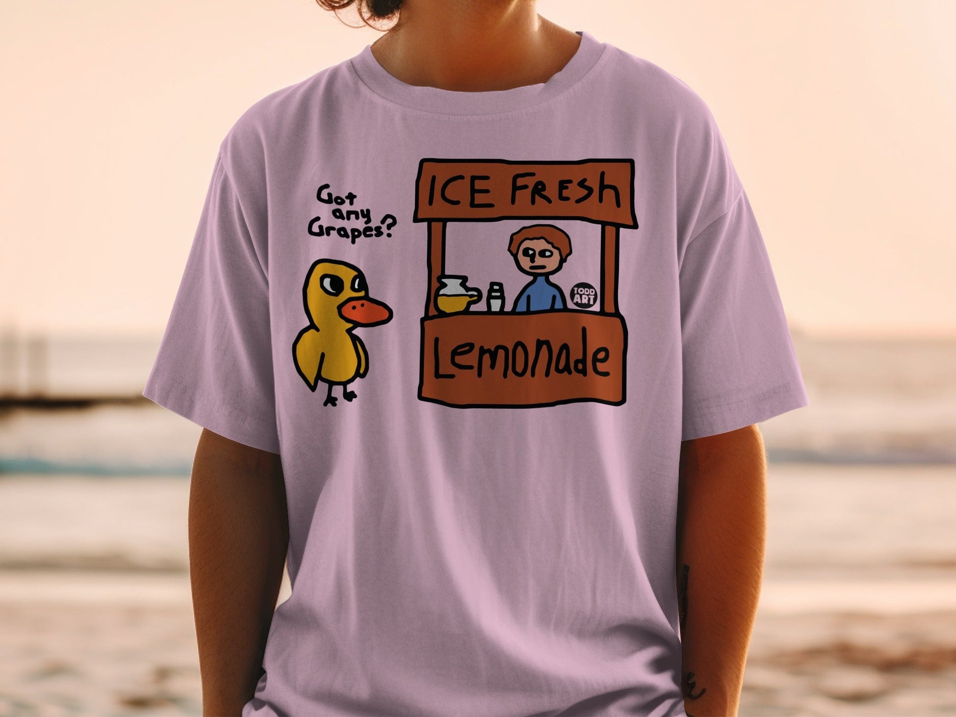 Cartoon duck asks about grapes at a lemonade stand on a light purple t-shirt.