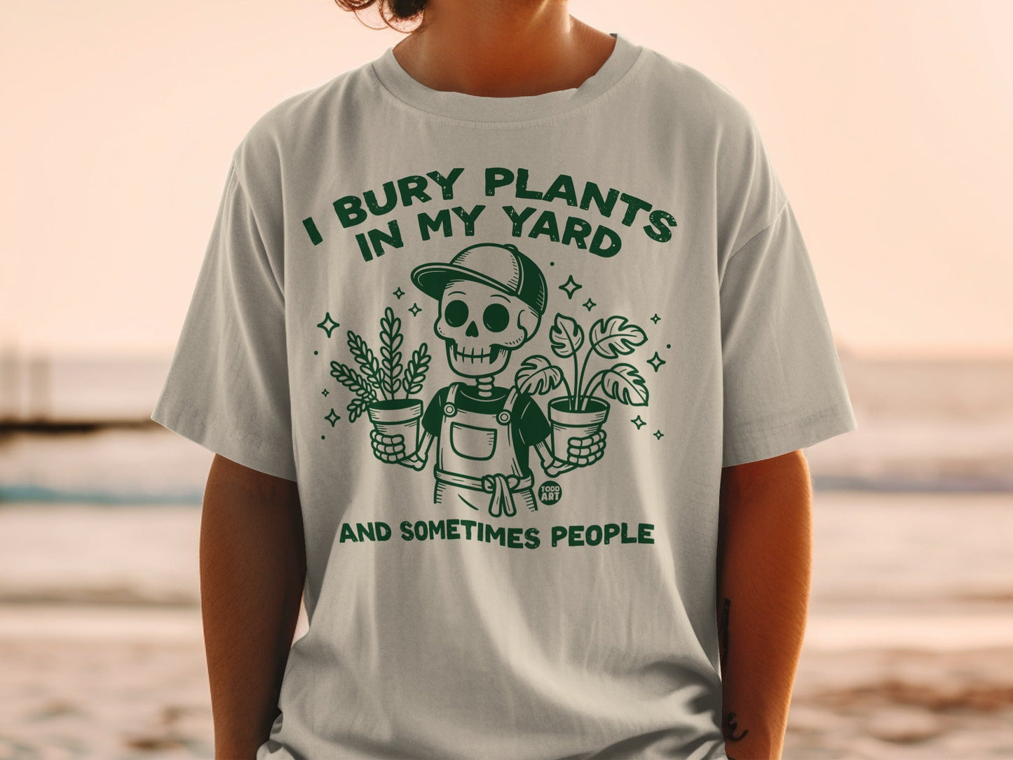 T-shirt with skeleton holding potted plants, text reads "I bury plants in my yard and sometimes people".