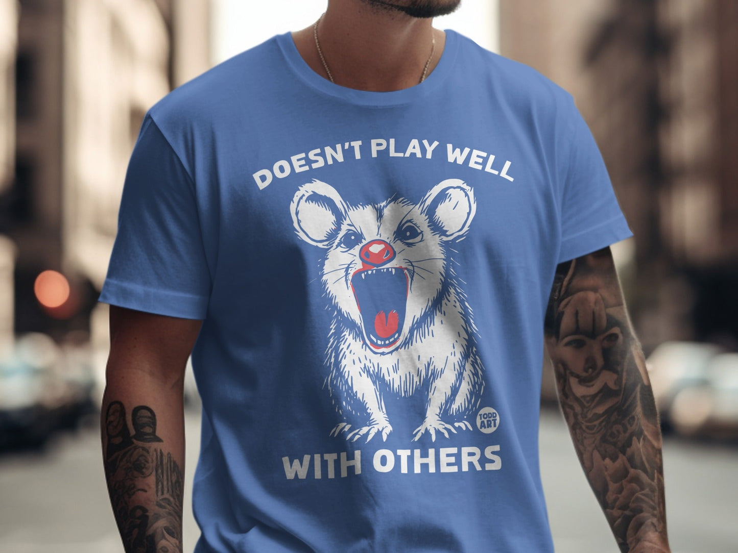 Blue t-shirt with a distressed opossum graphic and text "Doesn't Play Well With Others."